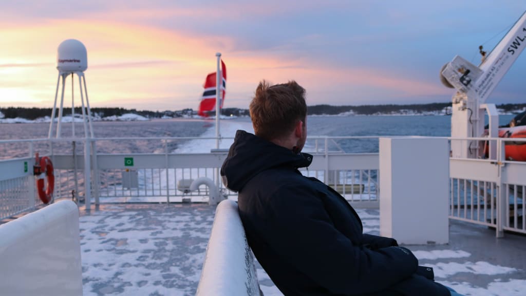 Man enjoying sunset boat trip from Bergen to Måløy with pink sky on deck