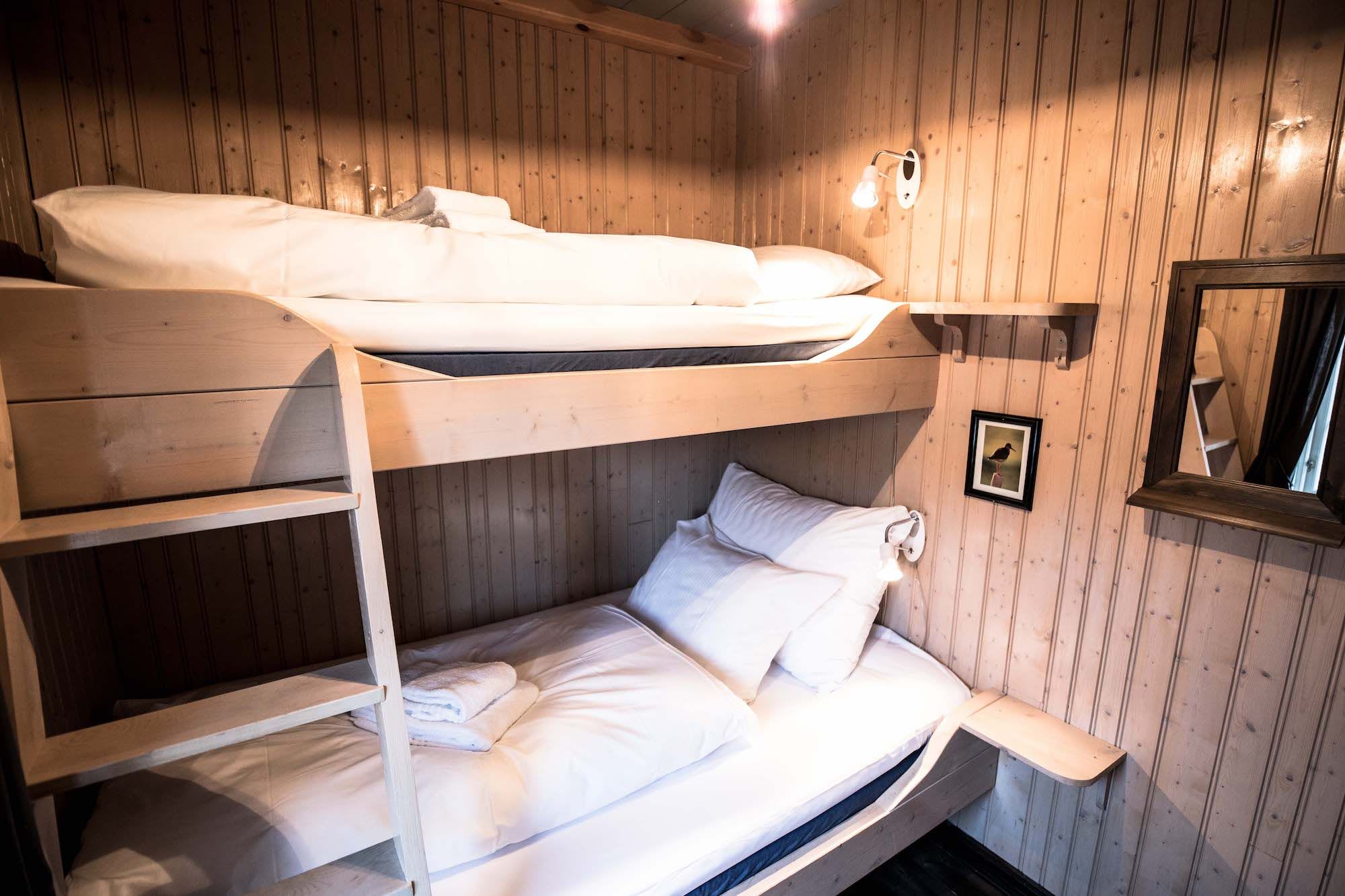 Bunk bed in a wooden cabin at Reine Rorbuer with mirror and lamp on the wall