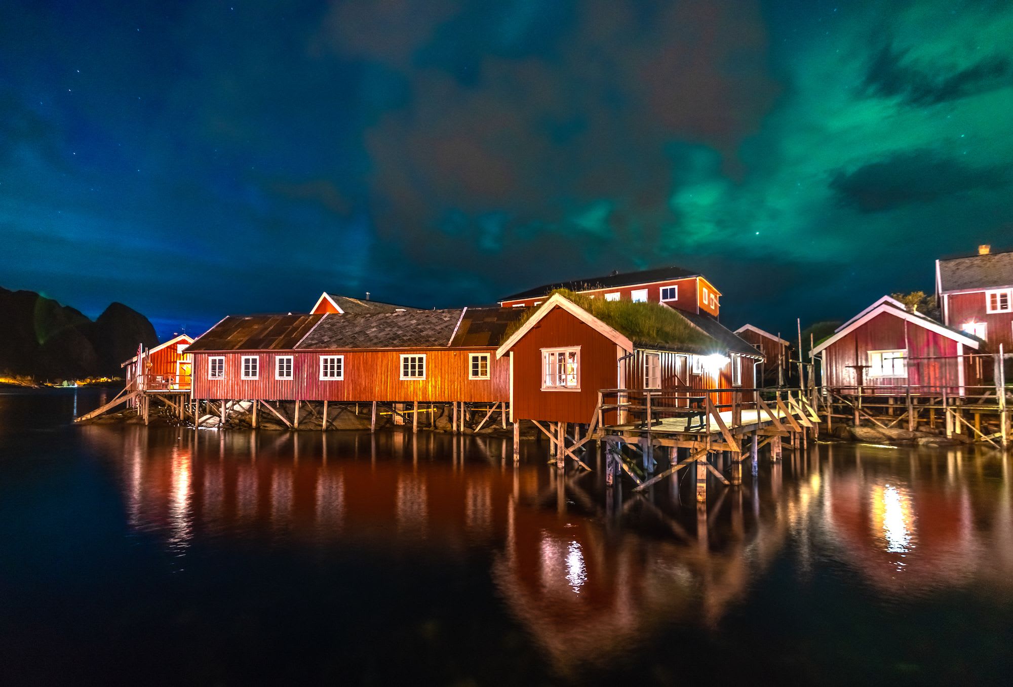 Fasade av Reine Rorbuer med dansende nordlys over