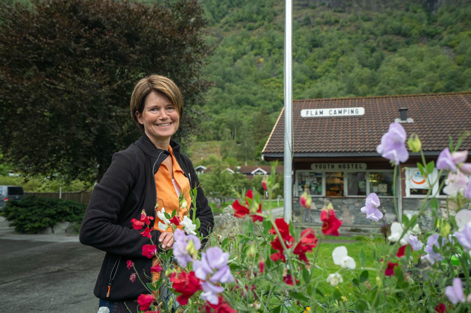 Hostess at Flåm camping welcomes everyone and is arranging fresh flowers on the tables.