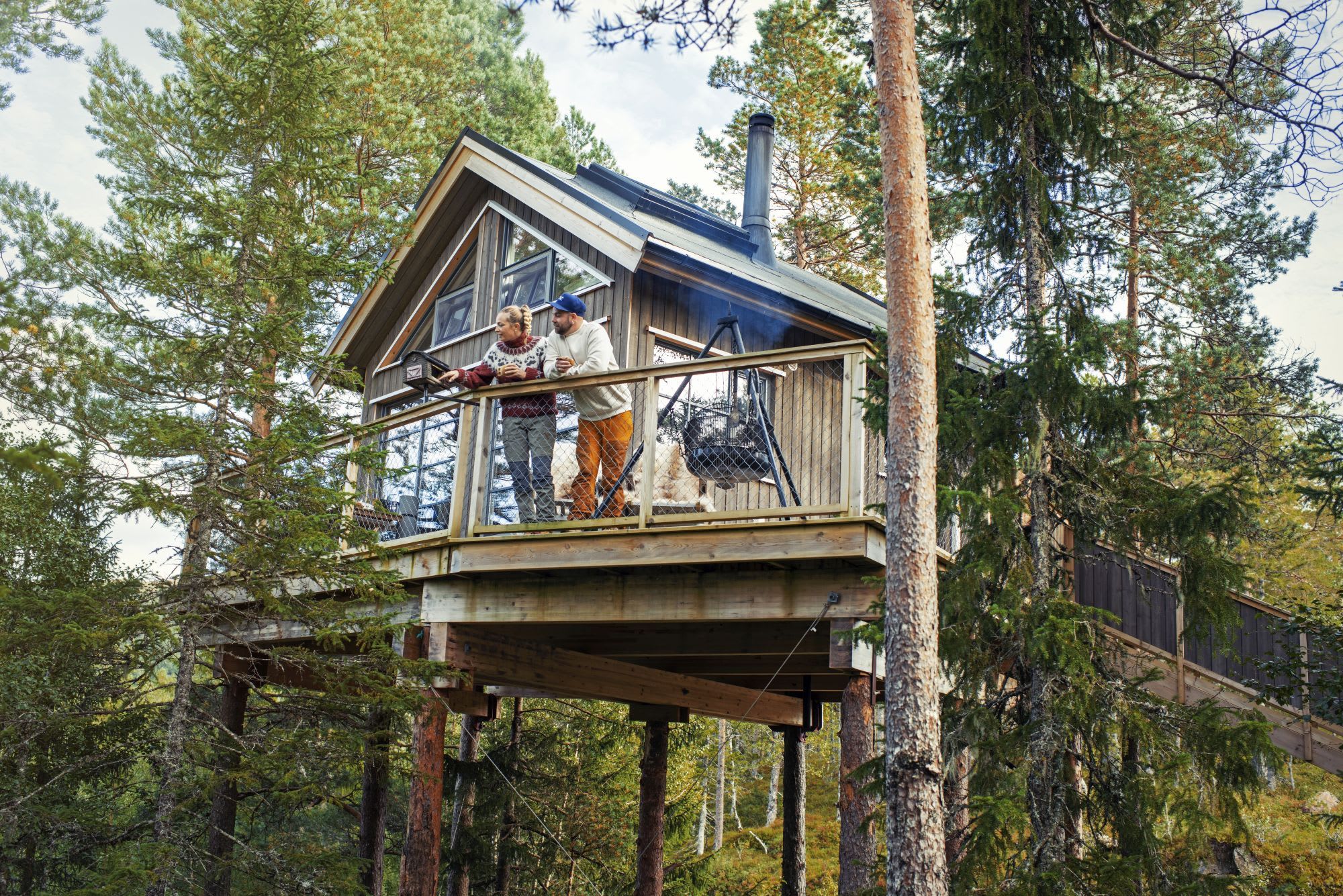 Couple relaxing in cozy treetop cabin overlooking forest in Trøndelag Norwa