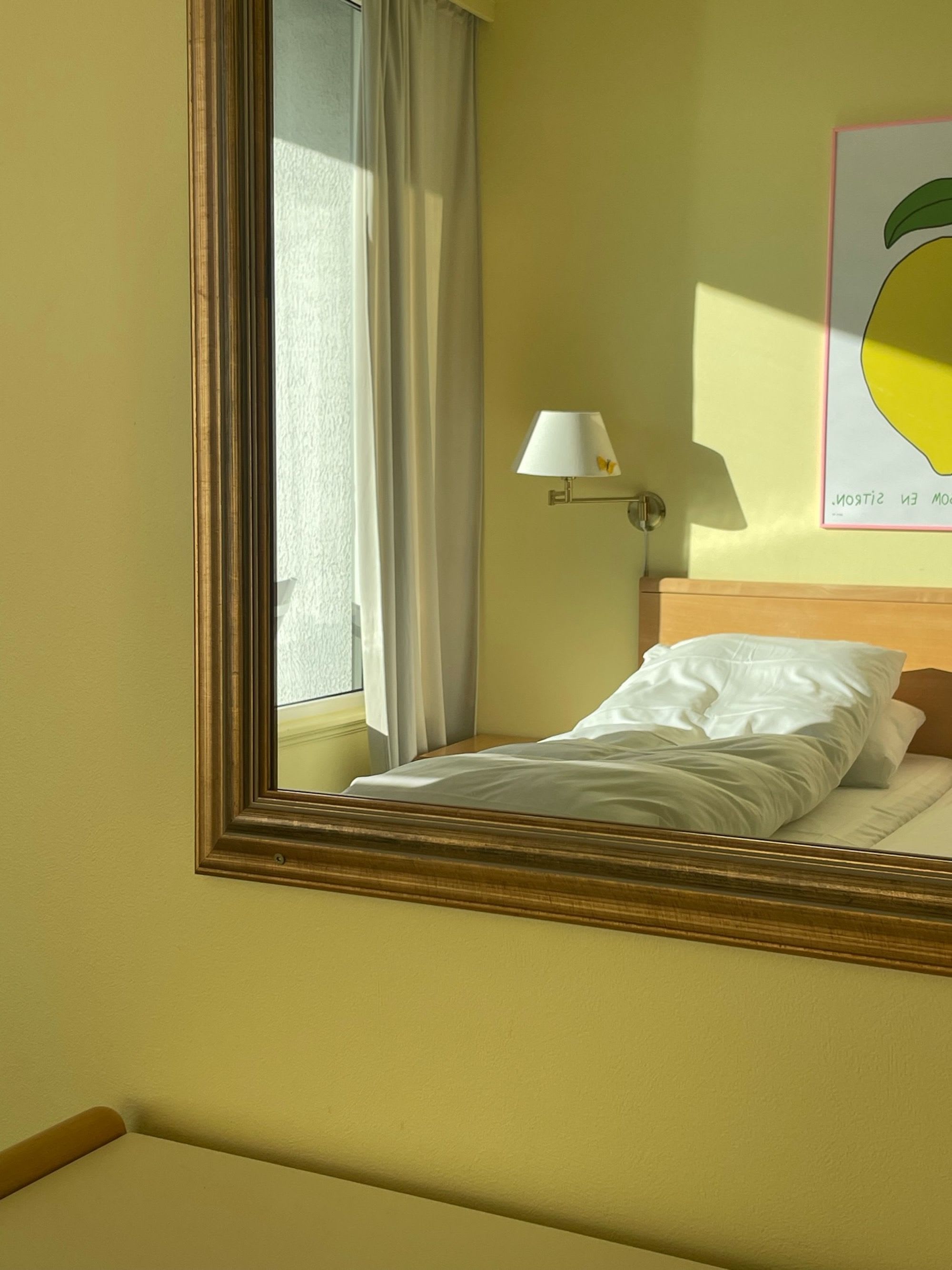 Gelbes Doppelzimmer im Balestrand Hotel im Spiegel, mit gemütlichem Bett und dekorativem Zitronengemälde an der Wand