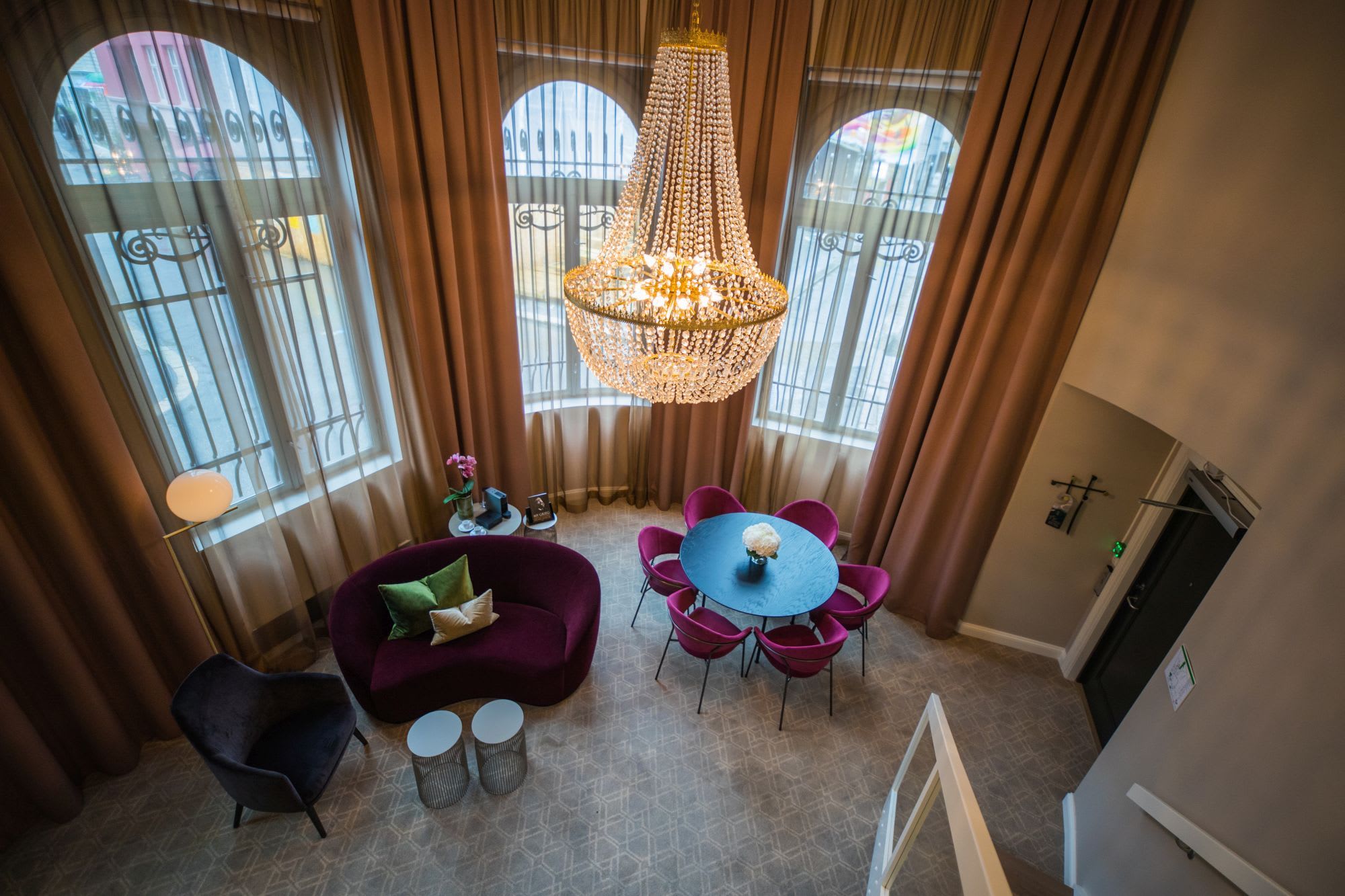Elegant hotel salon at Opus XVI Bergen with large bay windows, crystal chandelier and modern colorful furniture
