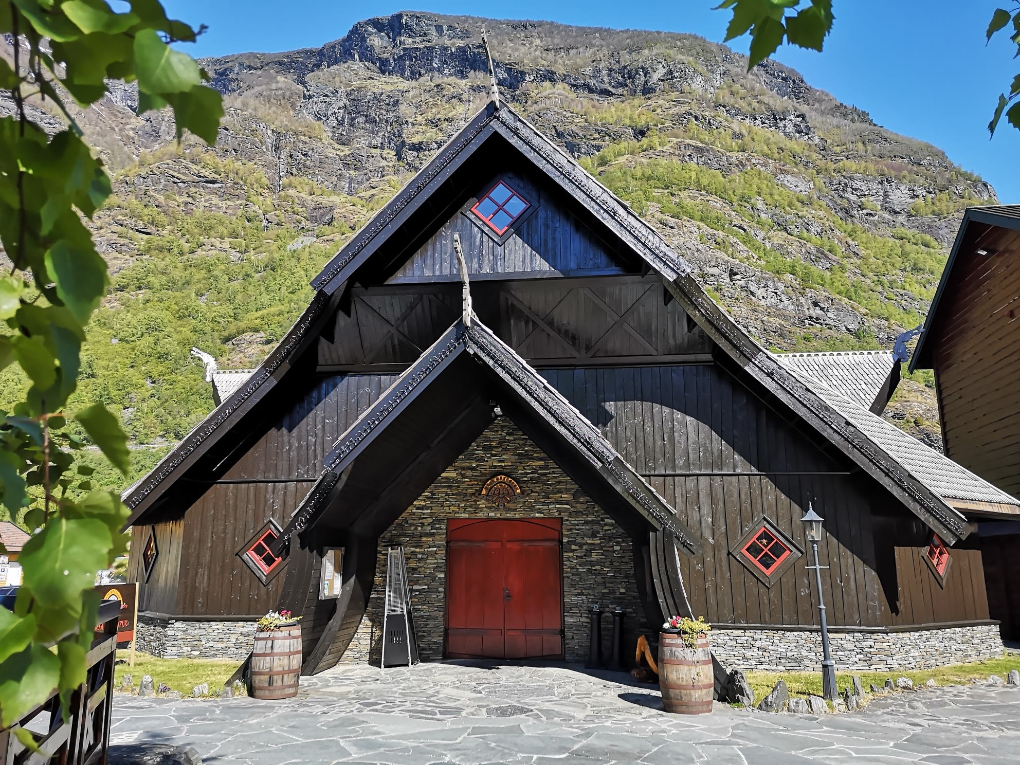 Markante Wikinger-Fassade des Ægir Gastropub in Flåm an einem sonnigen Sommertag mit Bergblick