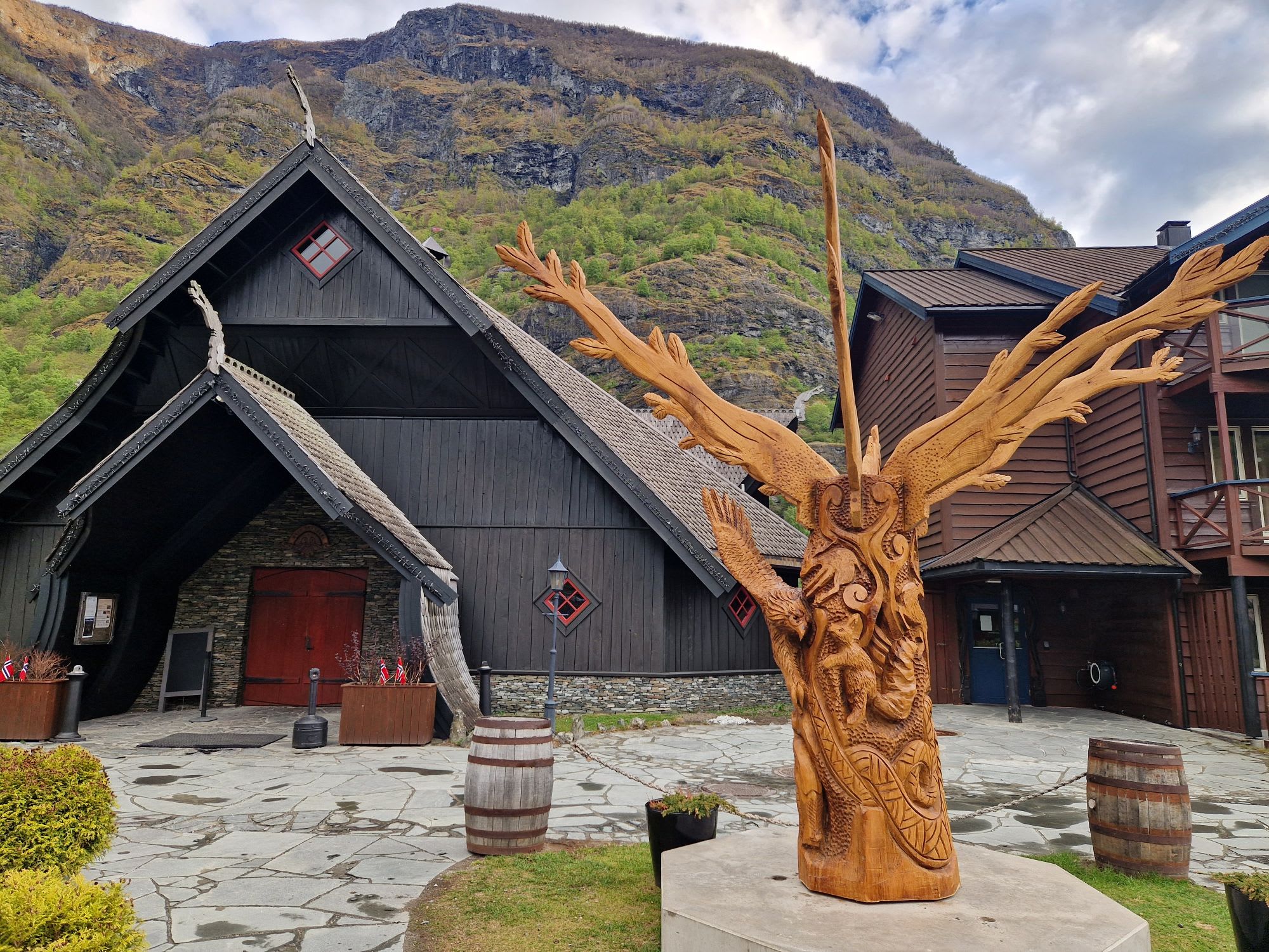 Außenbereich des Flåmsbrygga Hotels und Ægir Gastropubs in Flåm an einem Sommertag mit blauem Himmel und Bergen