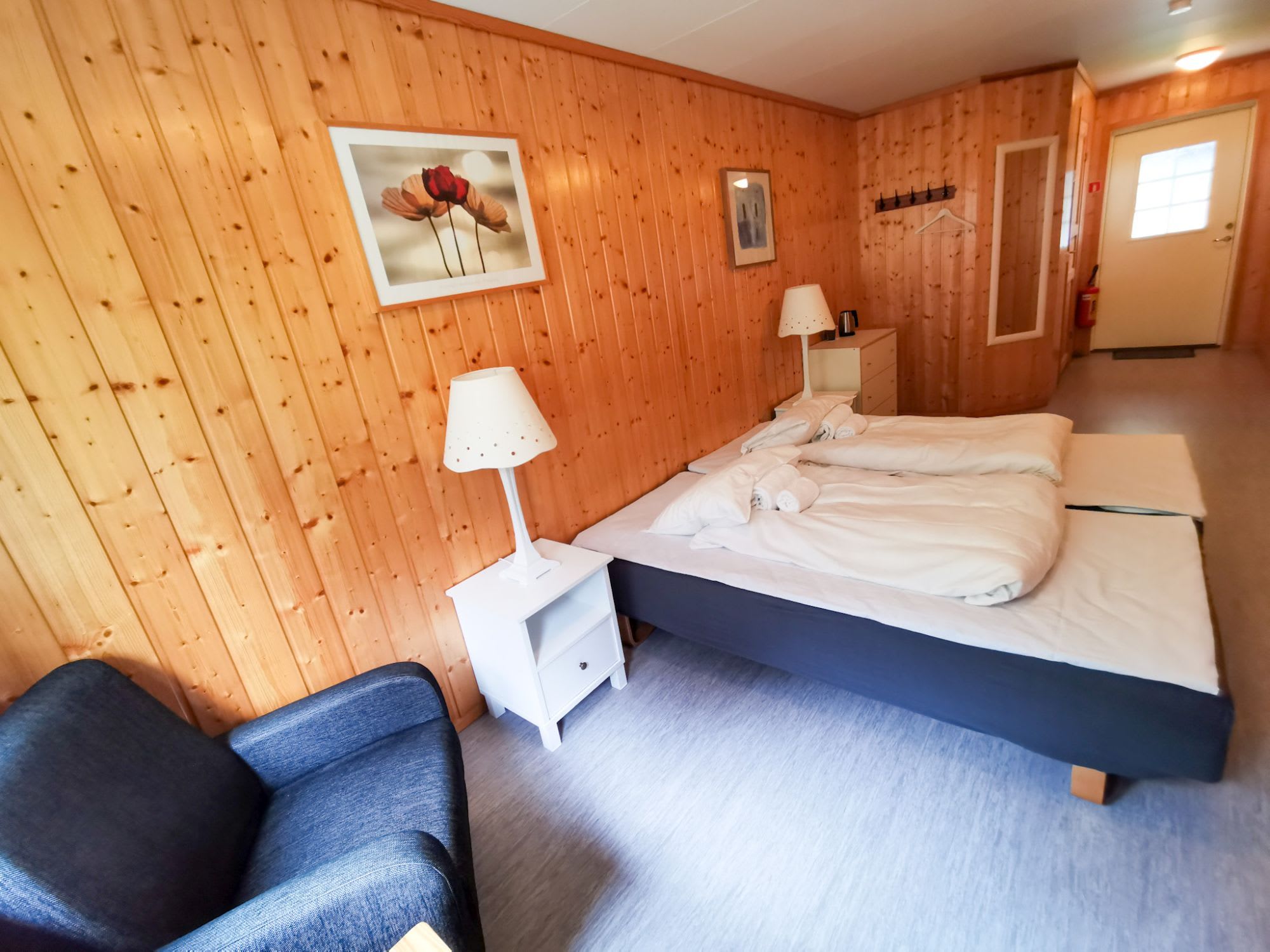 Lyst dobbeltrom på Gudvangen Fjordtel med trevegger og blå møbler - komfortabel overnatting i norske fjorder