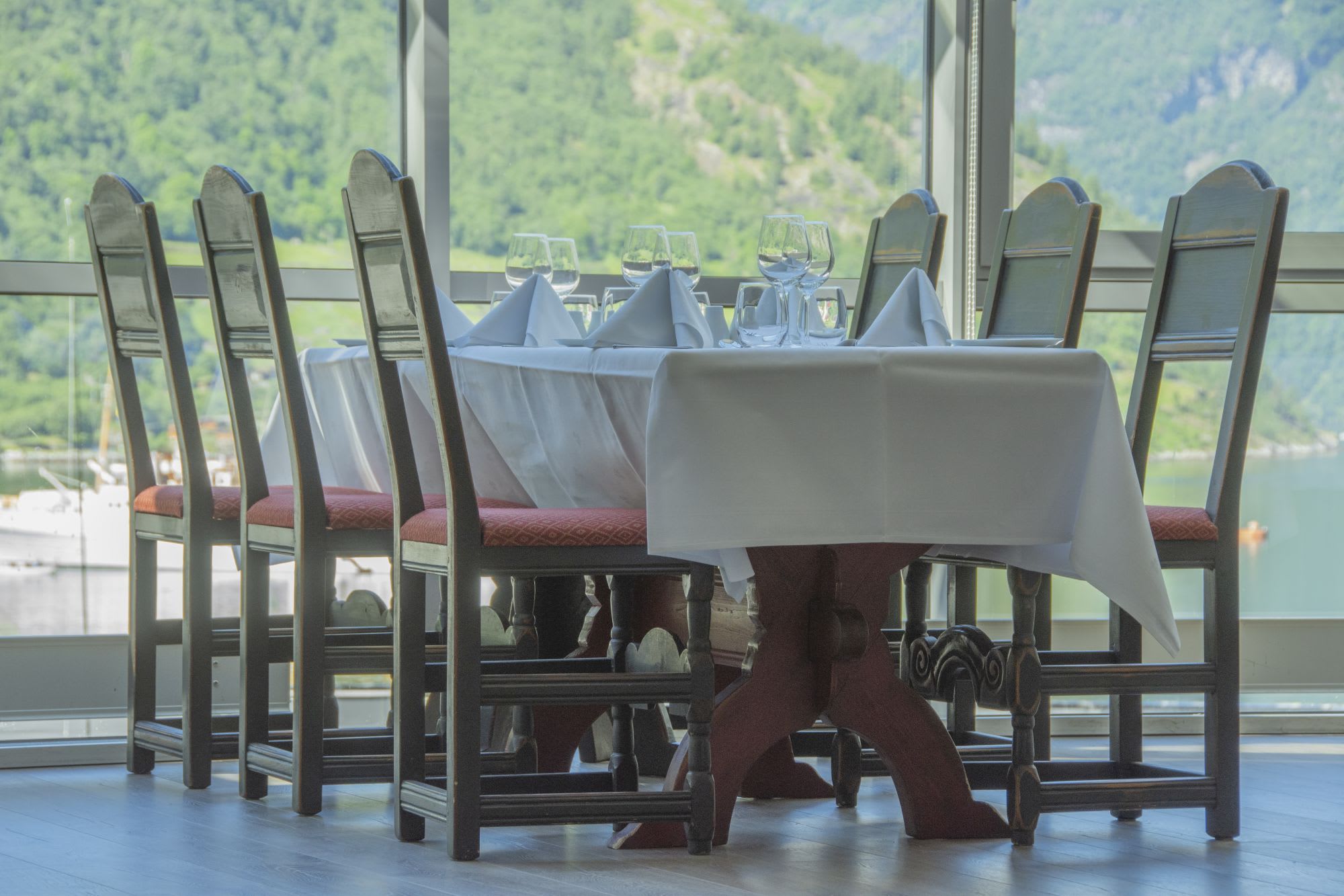 Fine dining table setup with white linens at Havila Hotel Geiranger restaurant with fjord panorama