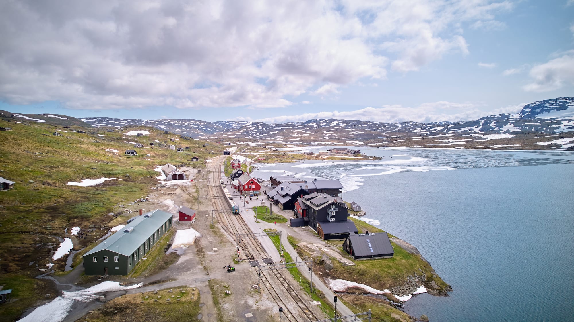 Flyfoto av Finse stasjon med Hotel Finse 1222 omgitt av brevatn og norsk fjelllandskap
