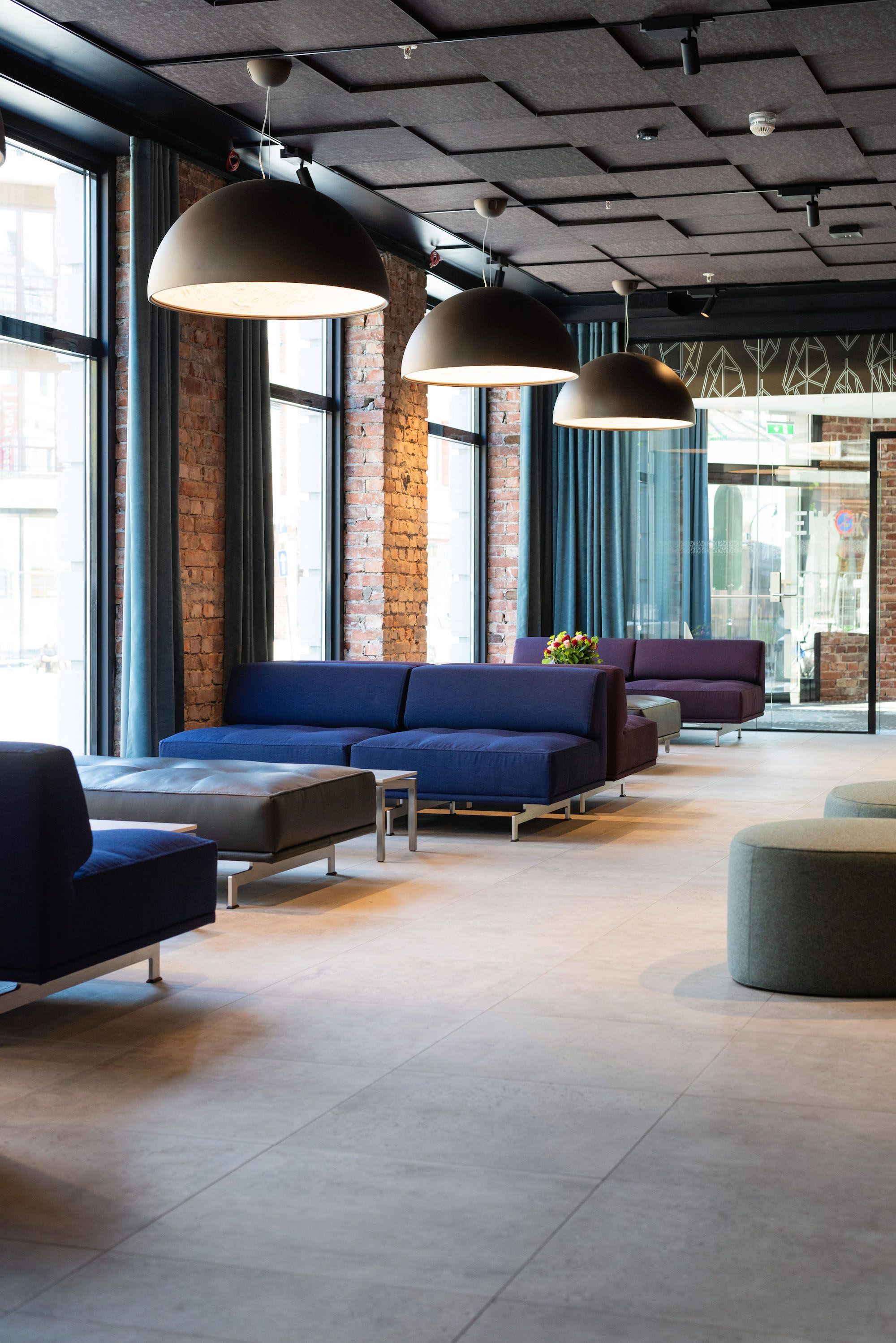 Modern hotel lobby interior featuring comfortable seating, warm lighting and large city windows