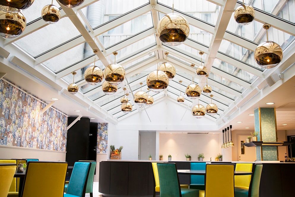 Lyst frokostrom på Thon Hotel Terminus Oslo med takvindu, gylne lamper, fargerike stoler
