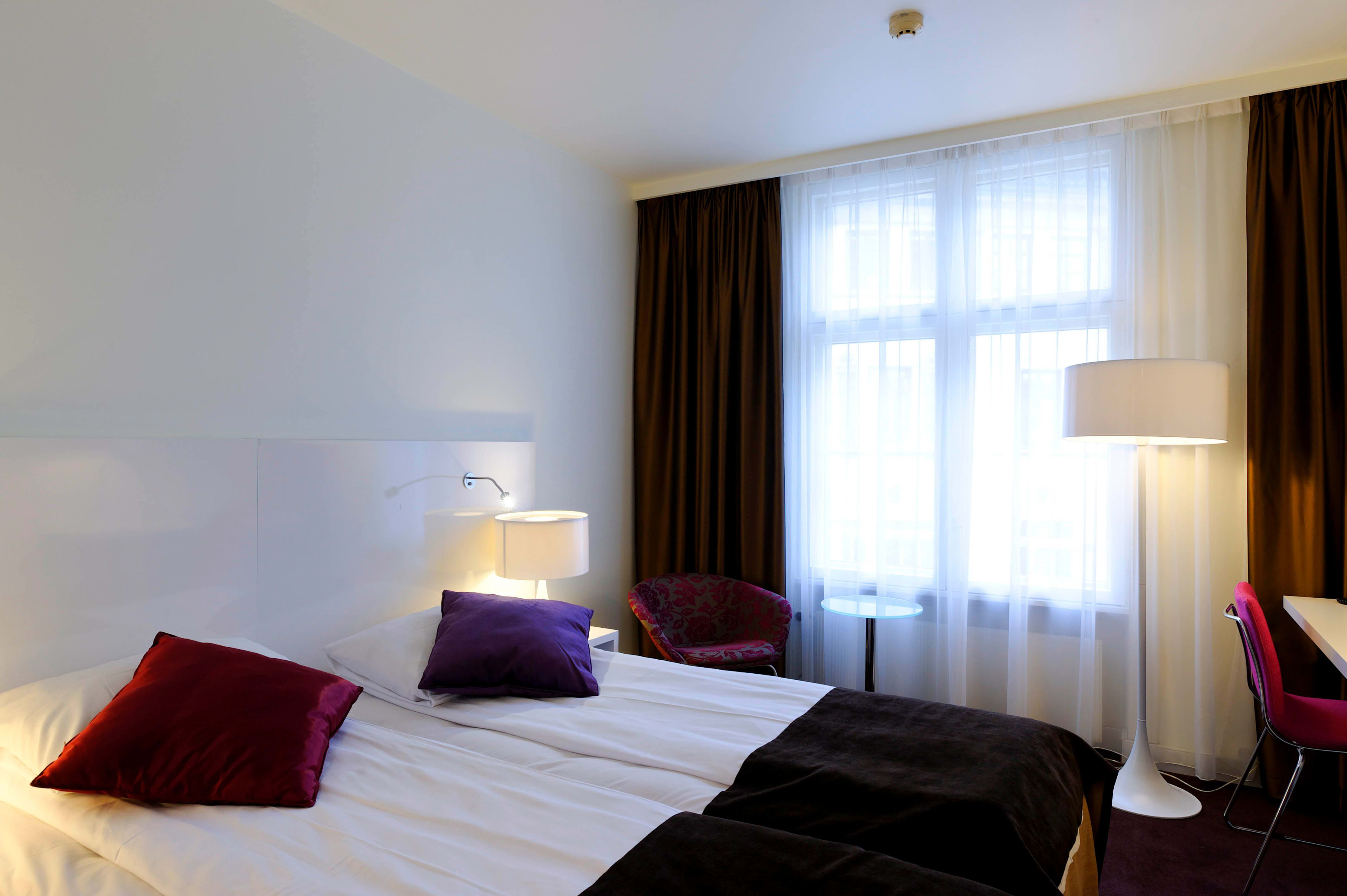 Tresengsrom på Thon Hotel Bristol Bergen med lilla sengetøy og utsikt over Bergen sentrum