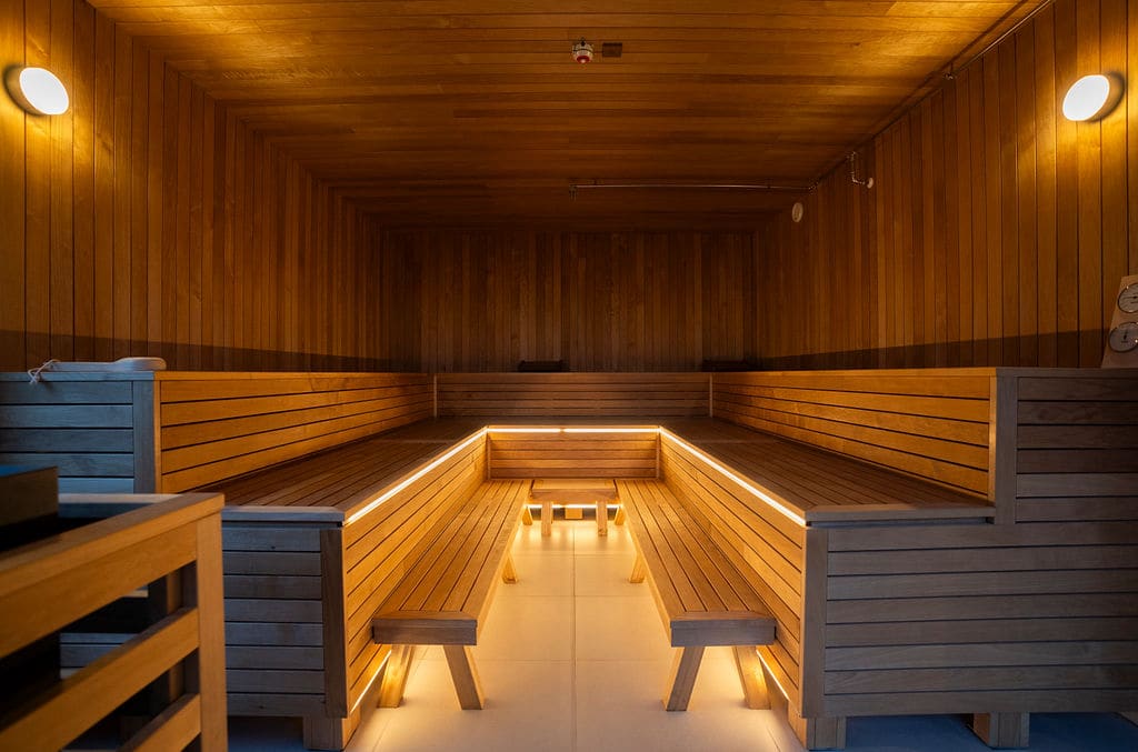 Spacious sauna interior at Vatnahalsen Høyfjellshotell with wooden benches and warm ambient lighting for relaxation.