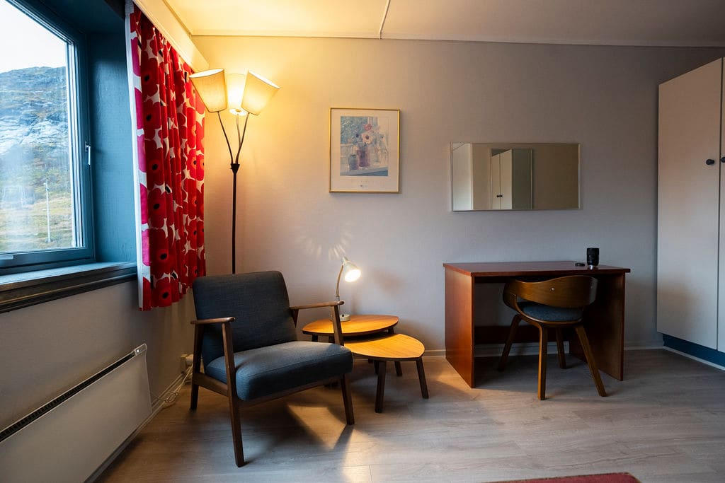 Comfortable reading corner with chair and desk in double room at Vatnahalsen Høyfjellshotell with mountain views