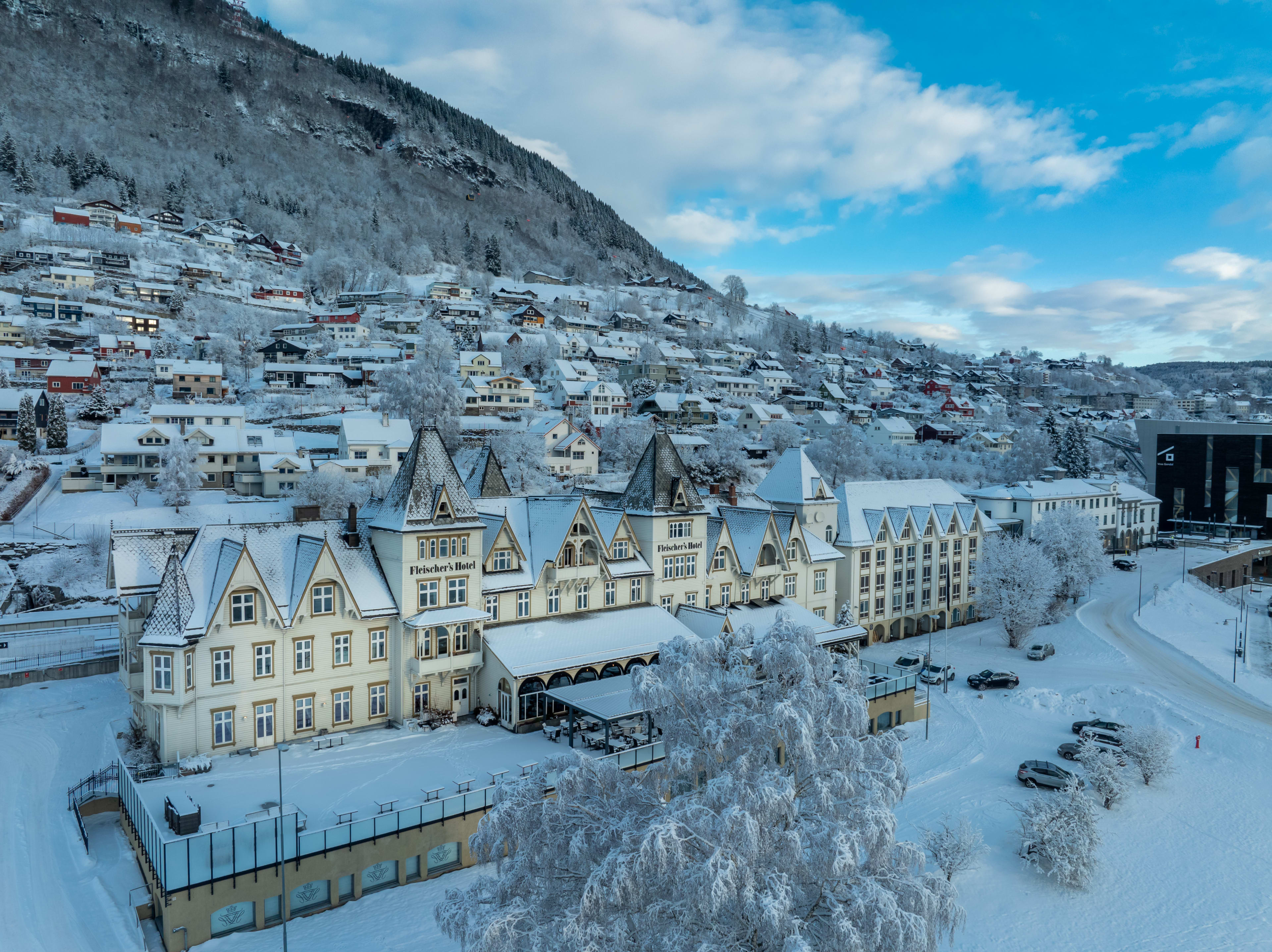 Aerial view of Fleischer's Hotel in Voss Norway during winter with snow-covered trees and clear blue sky