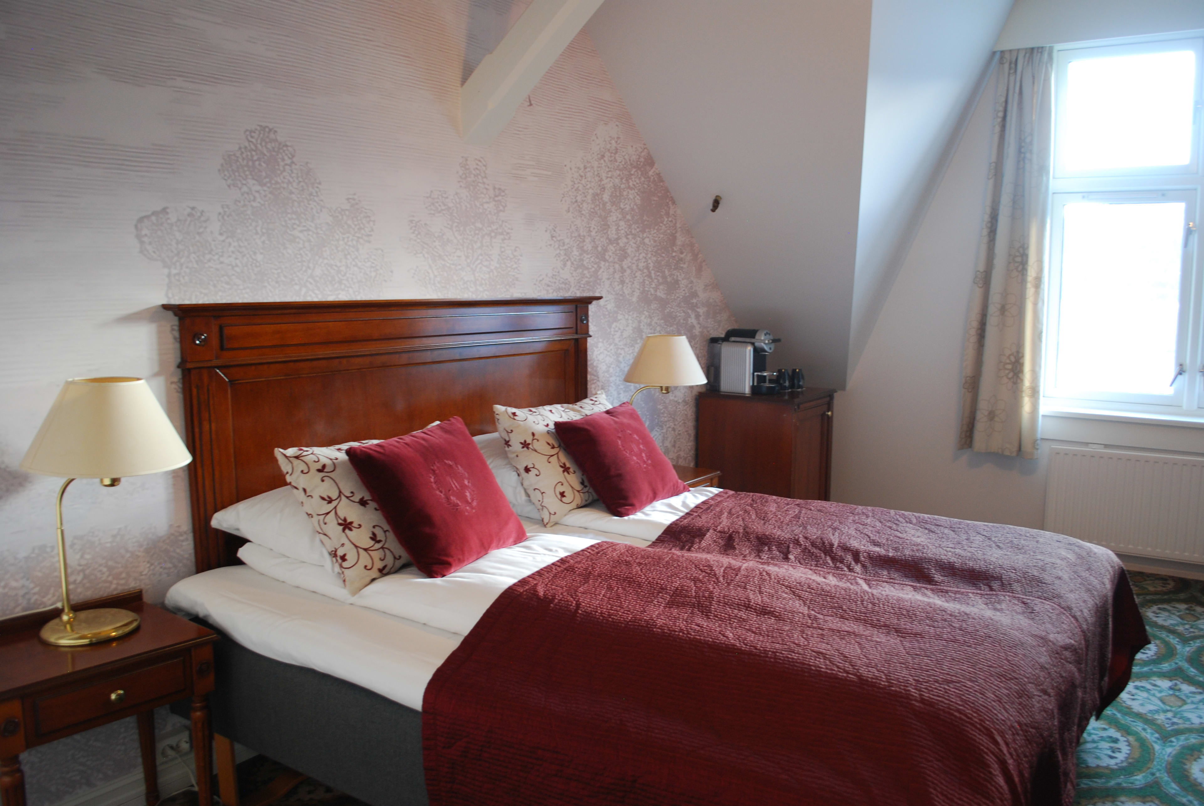 Historisk dobbeltrom på Fleischer's Hotel i Voss med klassiske møbler, blomstrete tapet og elegante lamper