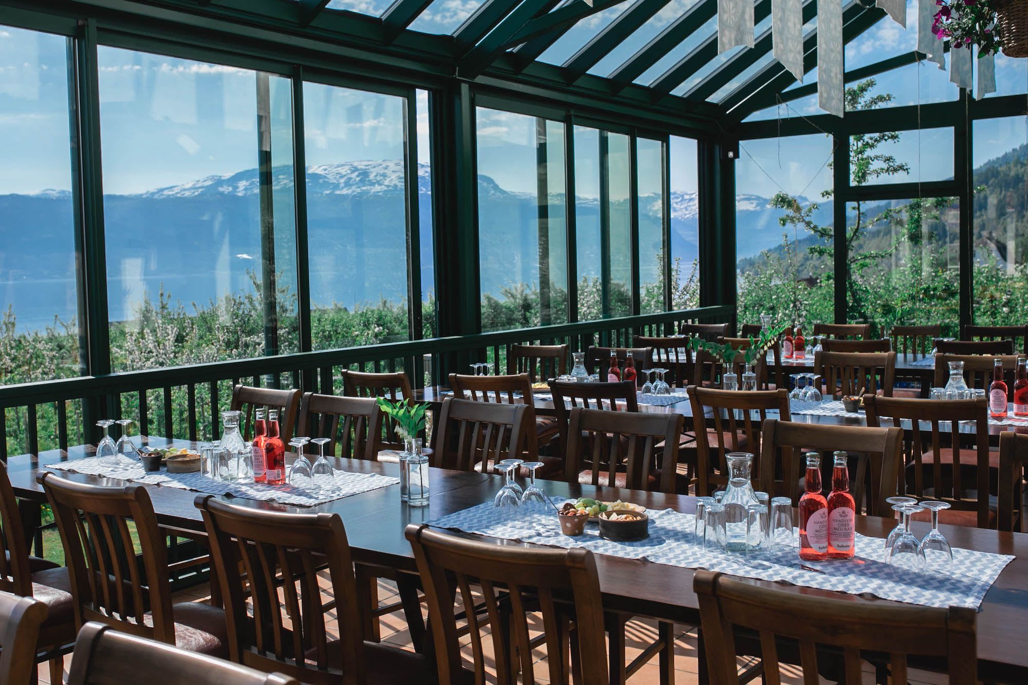 Elegant glass dining area offering breathtaking views of blooming orchards and mountain landscape.
