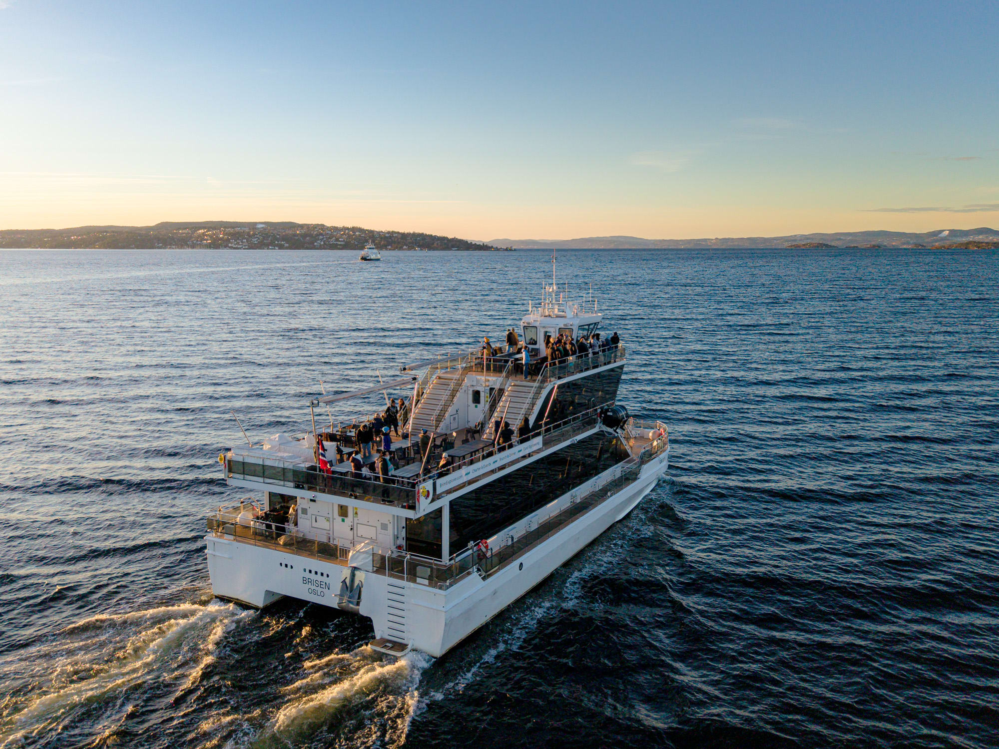 Hvit cruisebåt med gjester på dekk i Oslofjorden