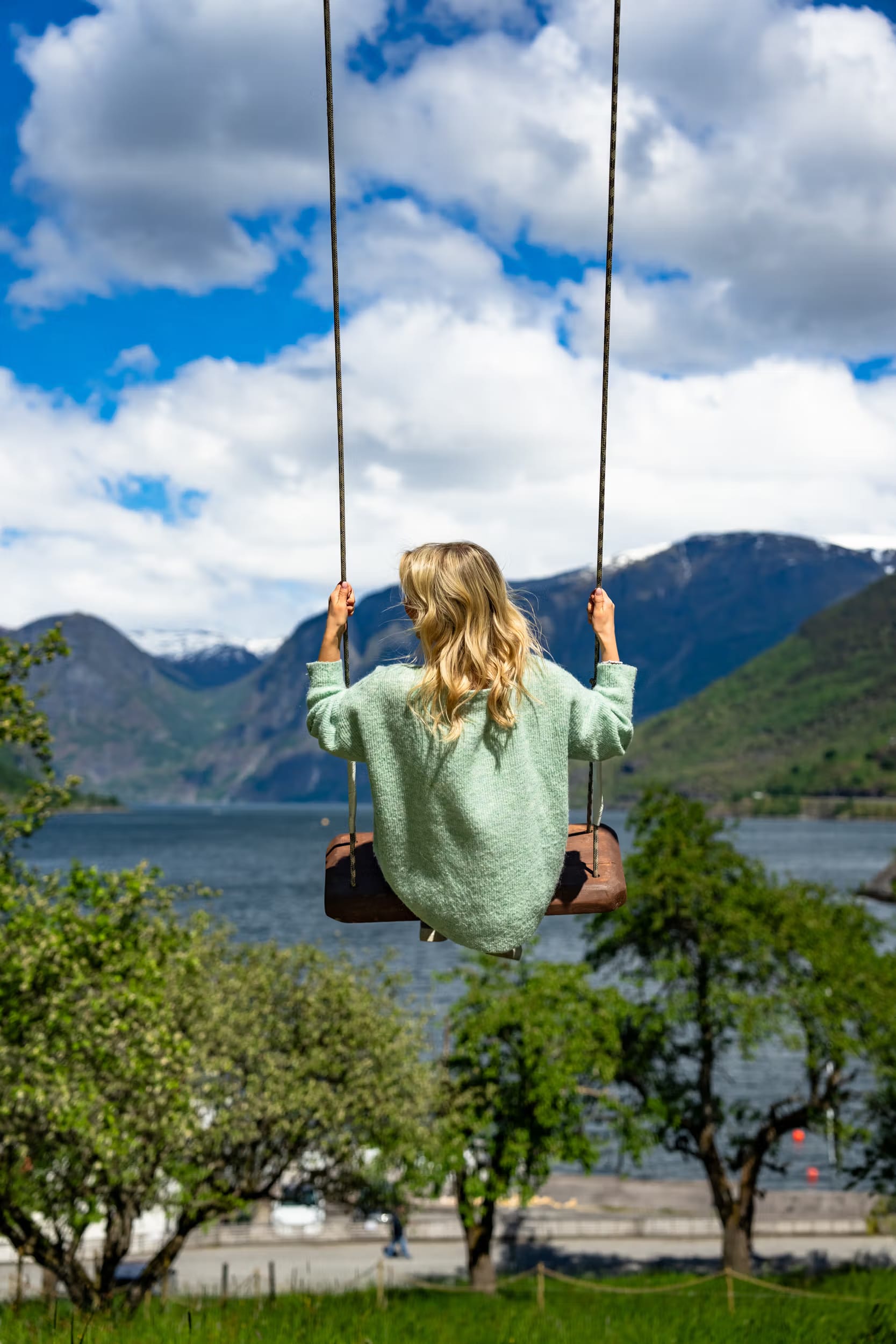 Tourist enjoying scenic swing photo opportunity at Flåm fjord farm