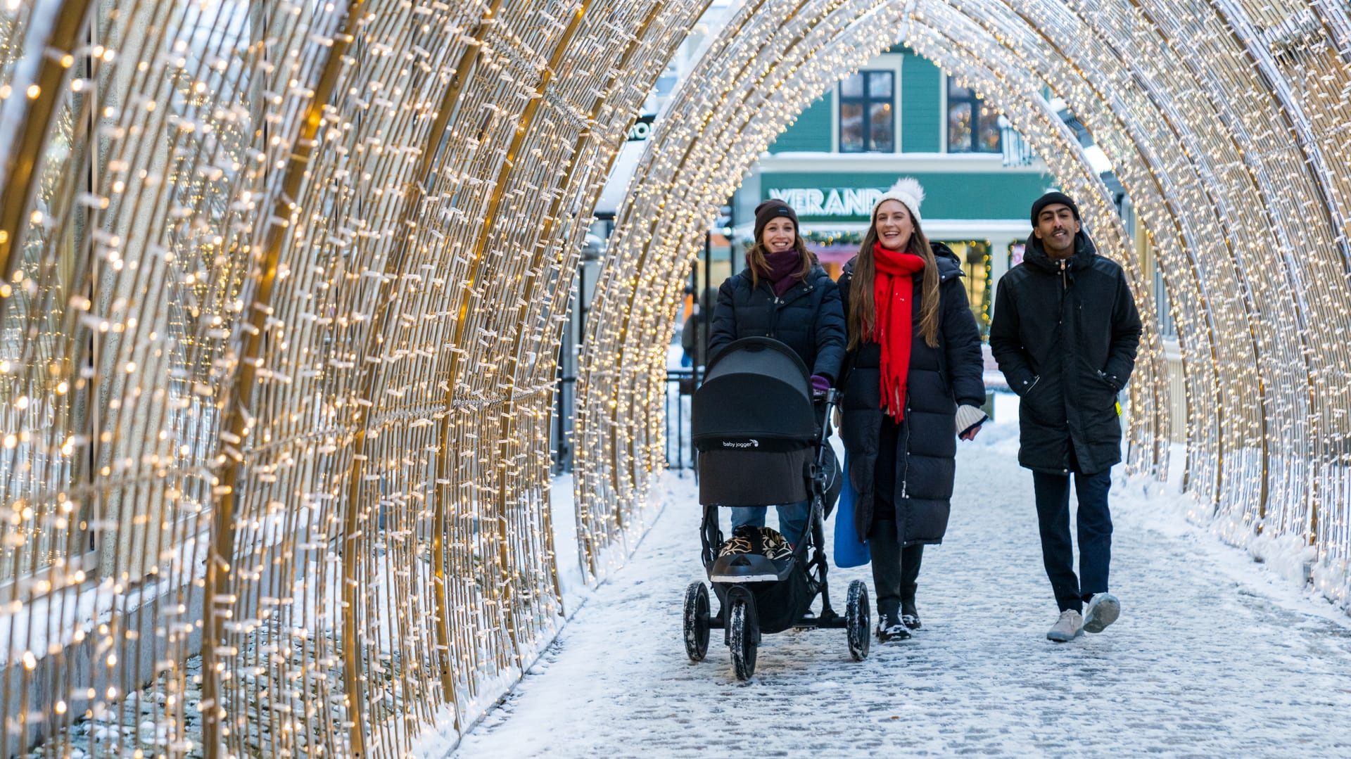 Family walking through magical illuminated Christmas light tunnel in Trondheim