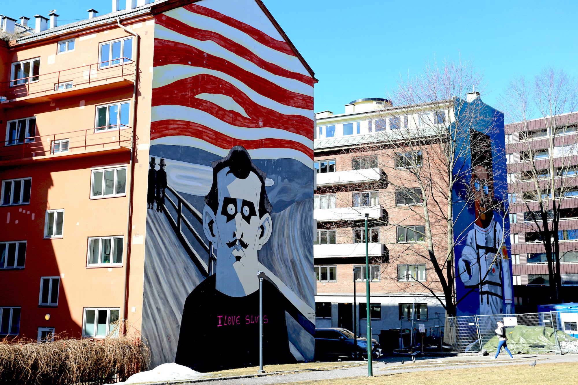 Urban murals on apartment buildings, one inspired by "The Scream" with swirling red and white waves.
