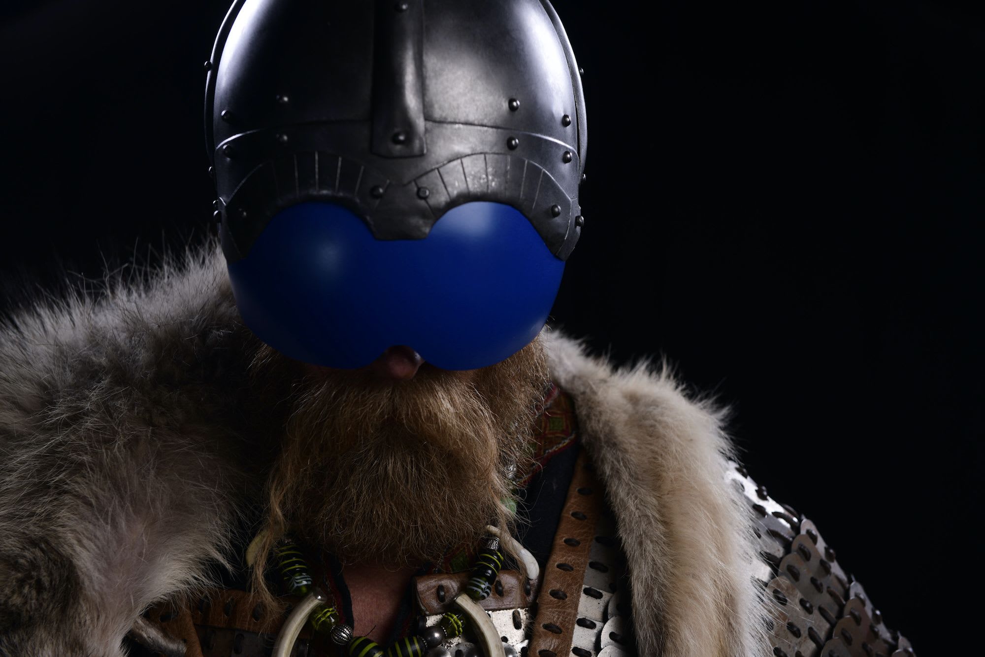 Person in Viking helmet and blue glasses in costume with fur cloak.