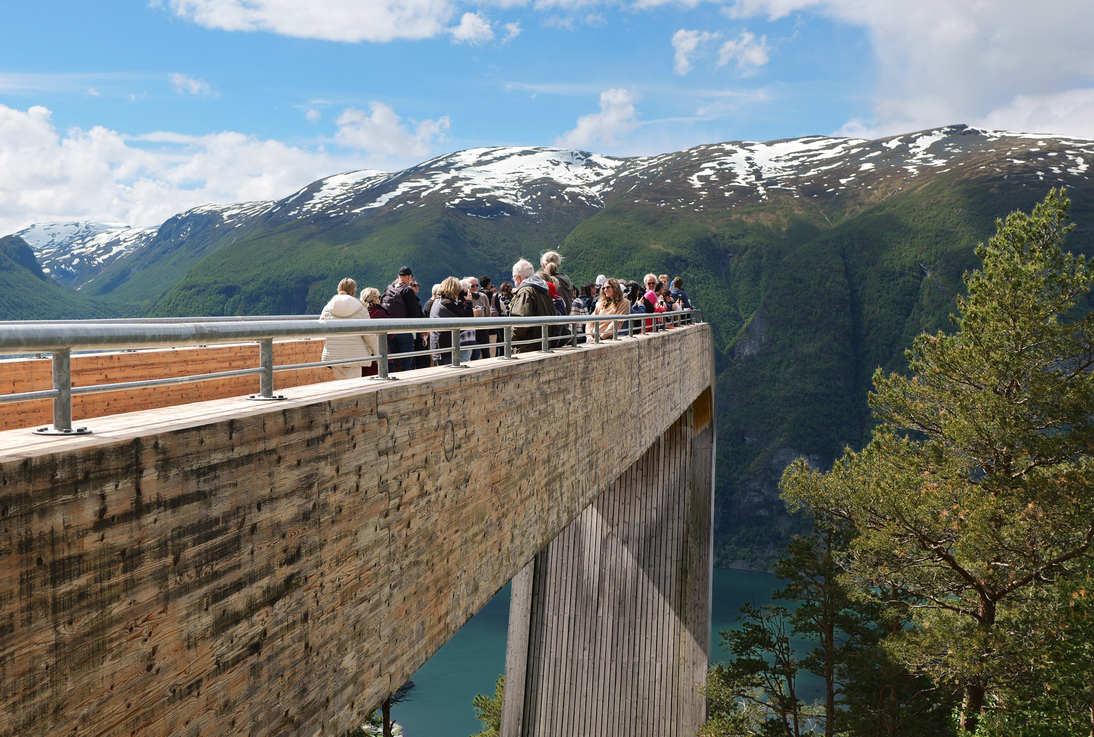 Folk på Stegastein utsiktspunkt over Aurlandsfjorden på en solrik sommerdag
