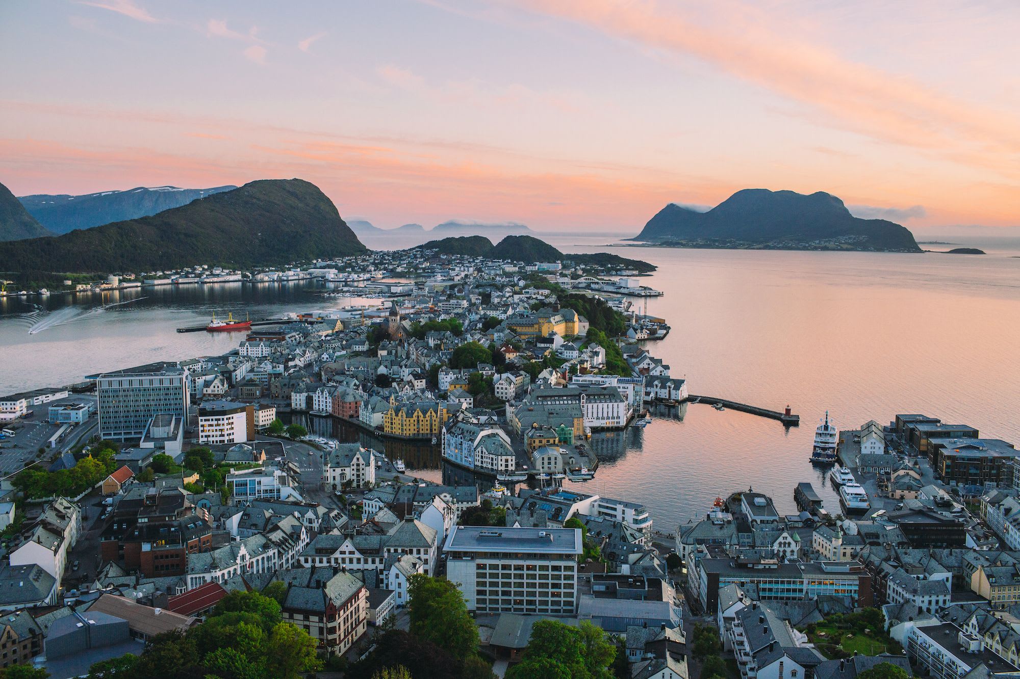 Sunset aerial of Ålesund’s colorful buildings, fjords, and mountains.