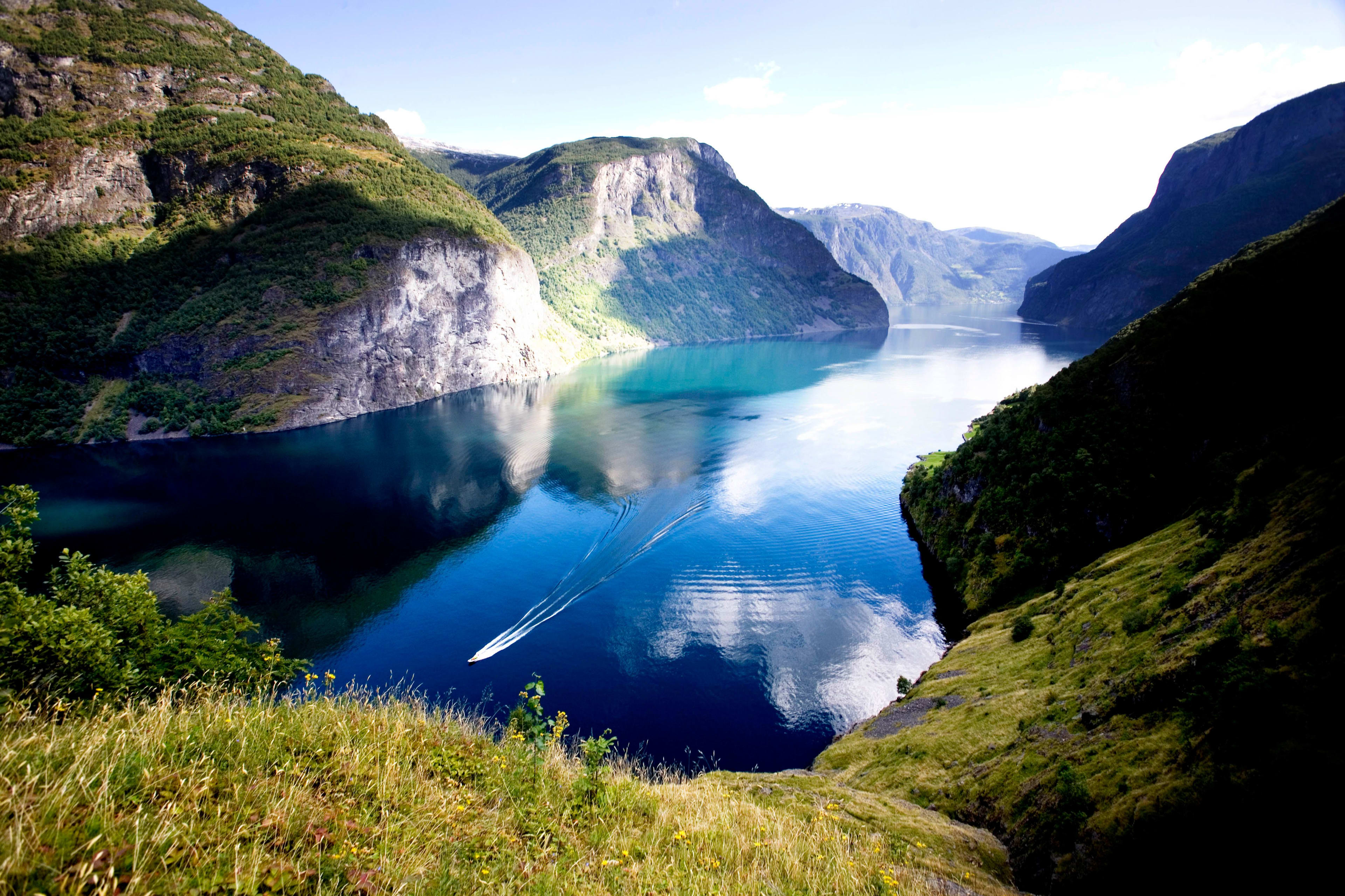 Aurlandsfjord in Flåm with crystal clear water, fjord cruise boats, and dramatic mountain landscapes