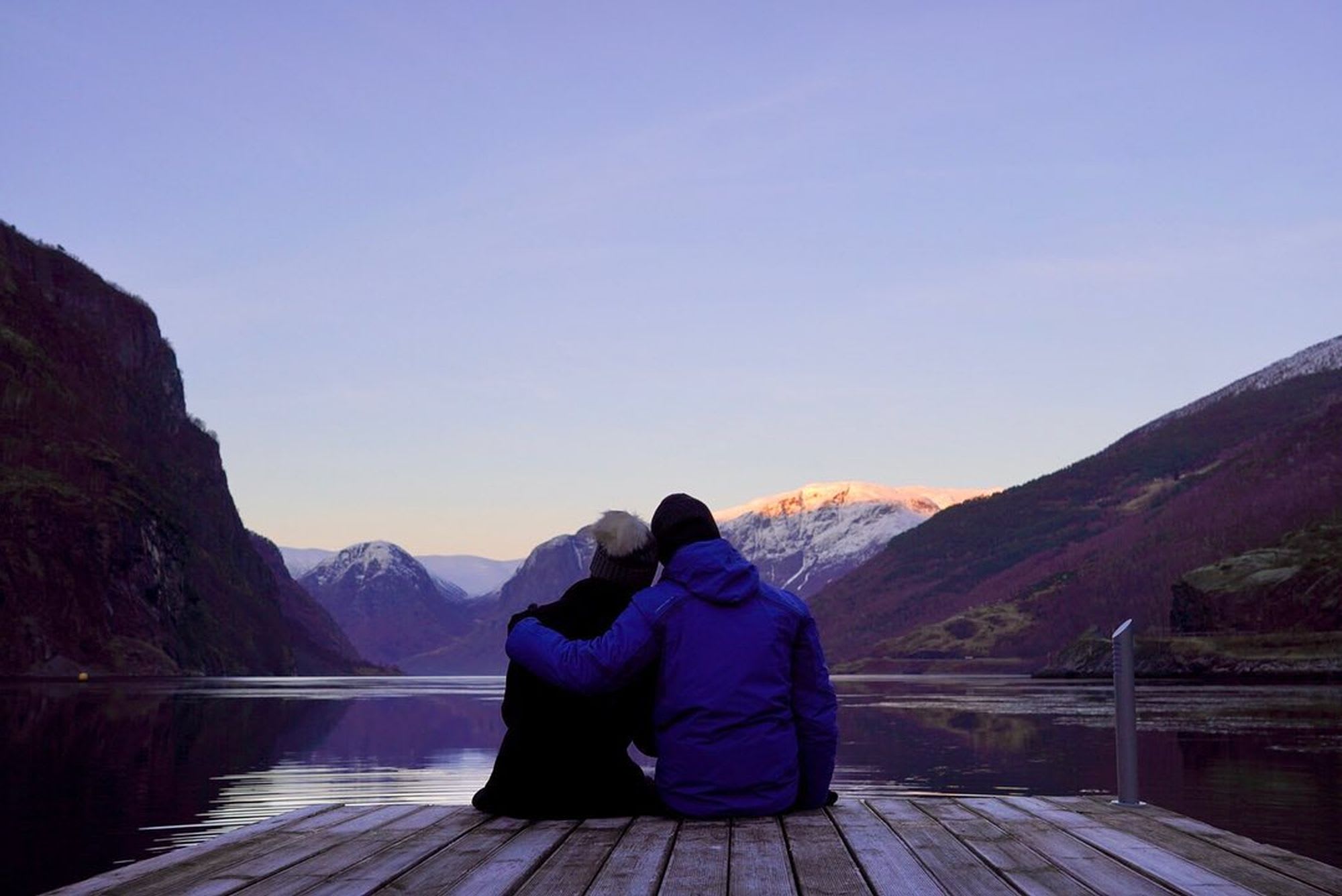 Romantic blue hour moment at Gudvangen harbour overlooking UNESCO-listed Nærøyfjord with dramatic winter mountain scenery