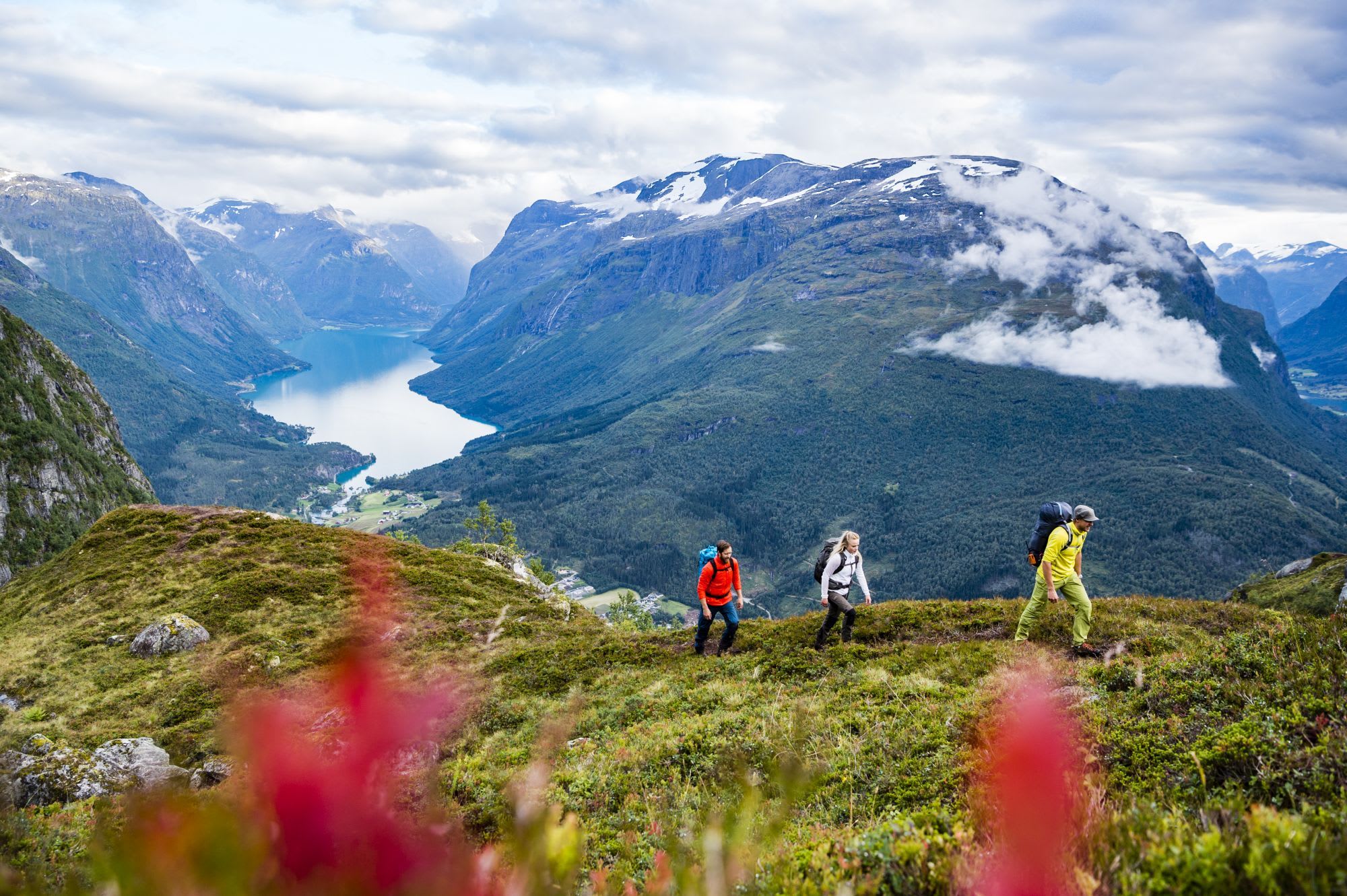 Turgåere på sti over fjord og fjell i skyene.