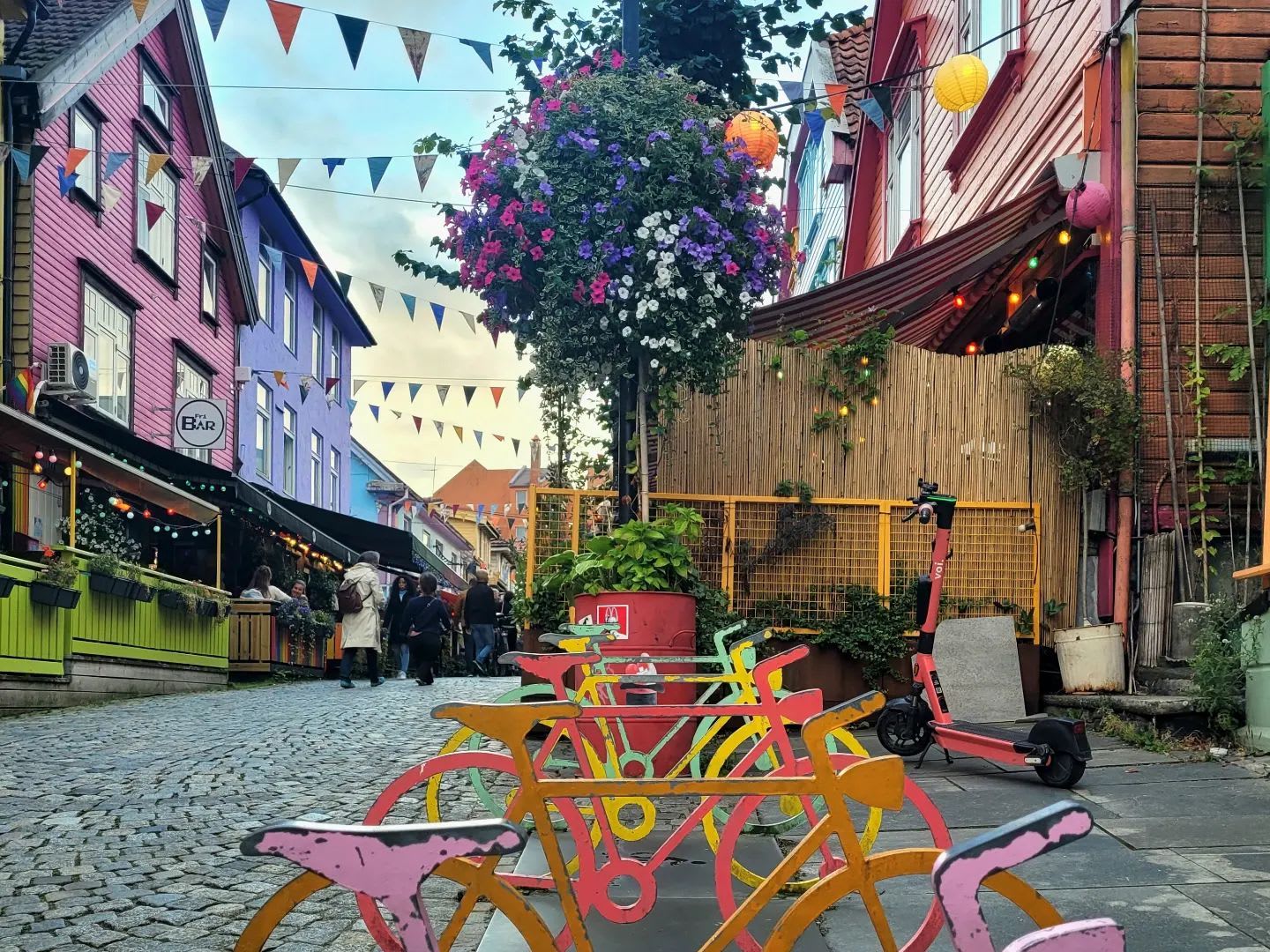 Bysykler i fargerike Fargegata i Stavanger med flagg, blomster og livlige kaféer