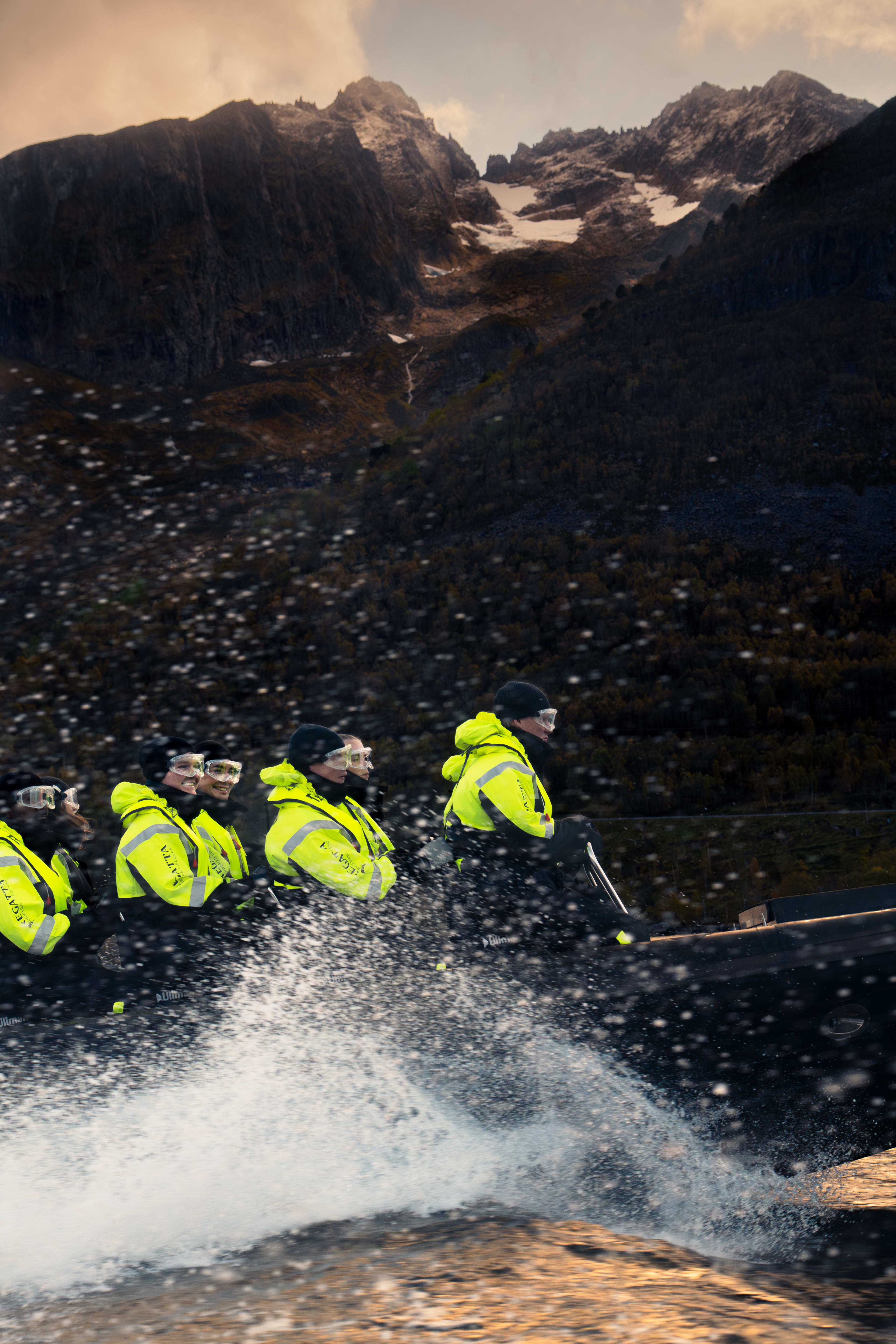 Passasjerer på RIB-båttur til Hjørundfjord fra Ålesund med vannsprut og dramatiske fjell i bakgrunnen