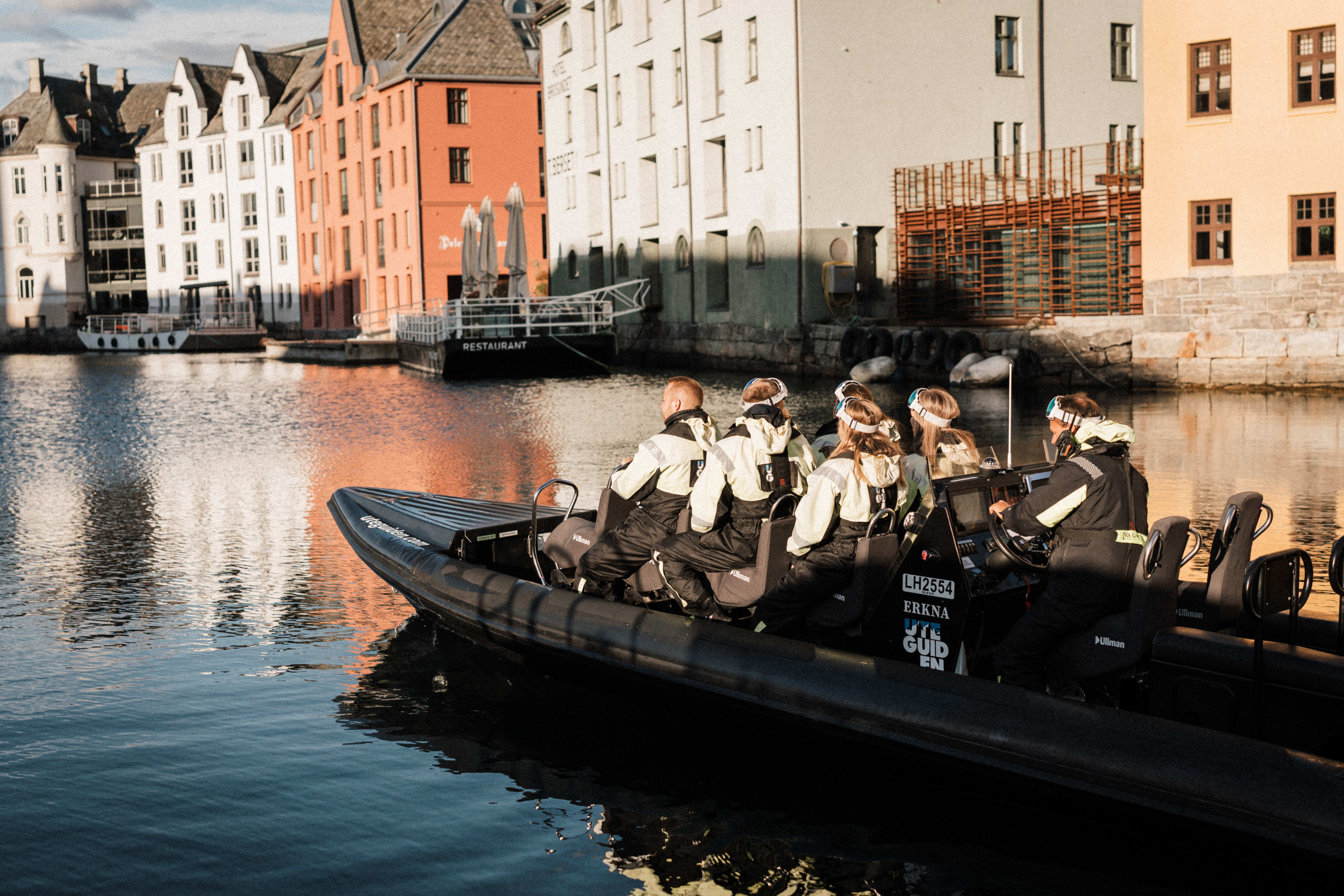 RIB boat tour from Ålesund harbor with passengers surrounded by colorful Art Nouveau buildings along the Norwegian coast