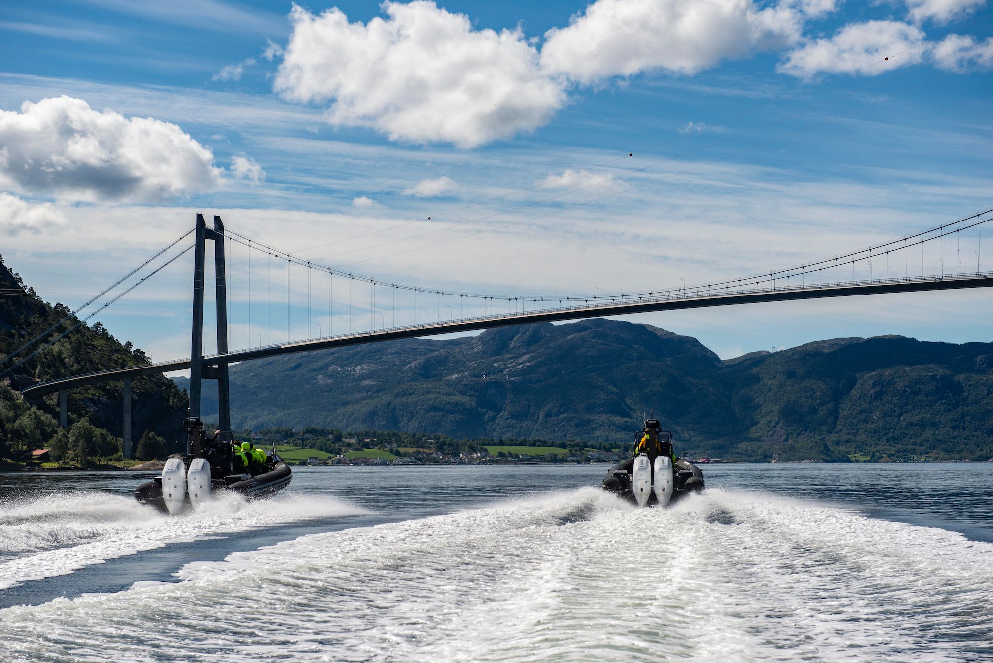 RIB Boats on Lysefjord with a suspension bridge and green mountains in the background.