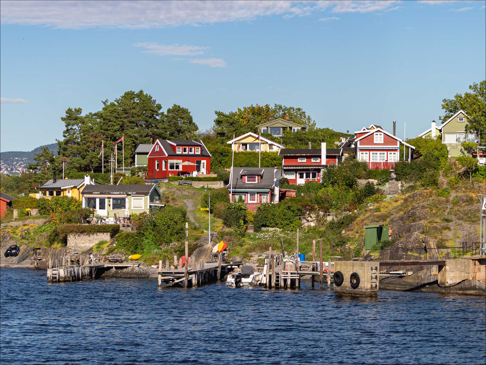 Colorful Norwegian coastal houses with docks on Oslo archipelago during peaceful fjord cruise