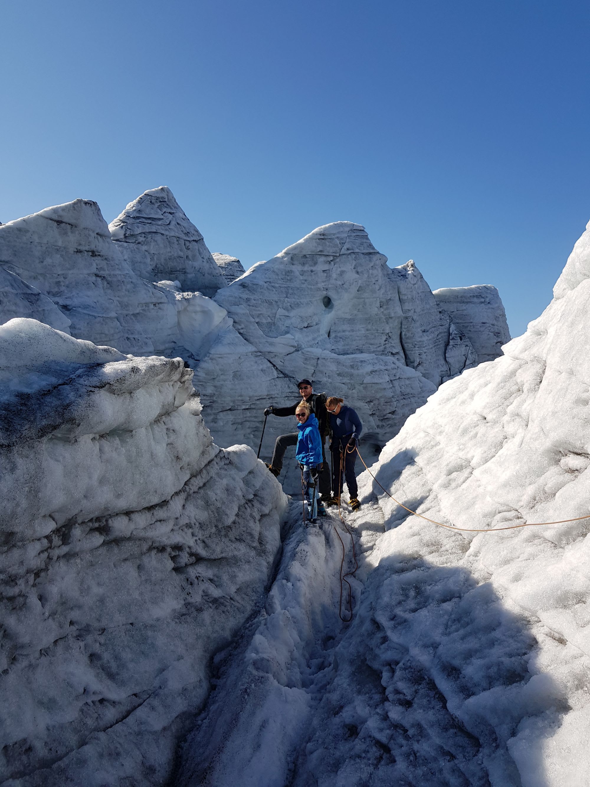 Tre klatrere står på breen, omringet av isformasjoner, klare for å takle det utfordrende terrenget.