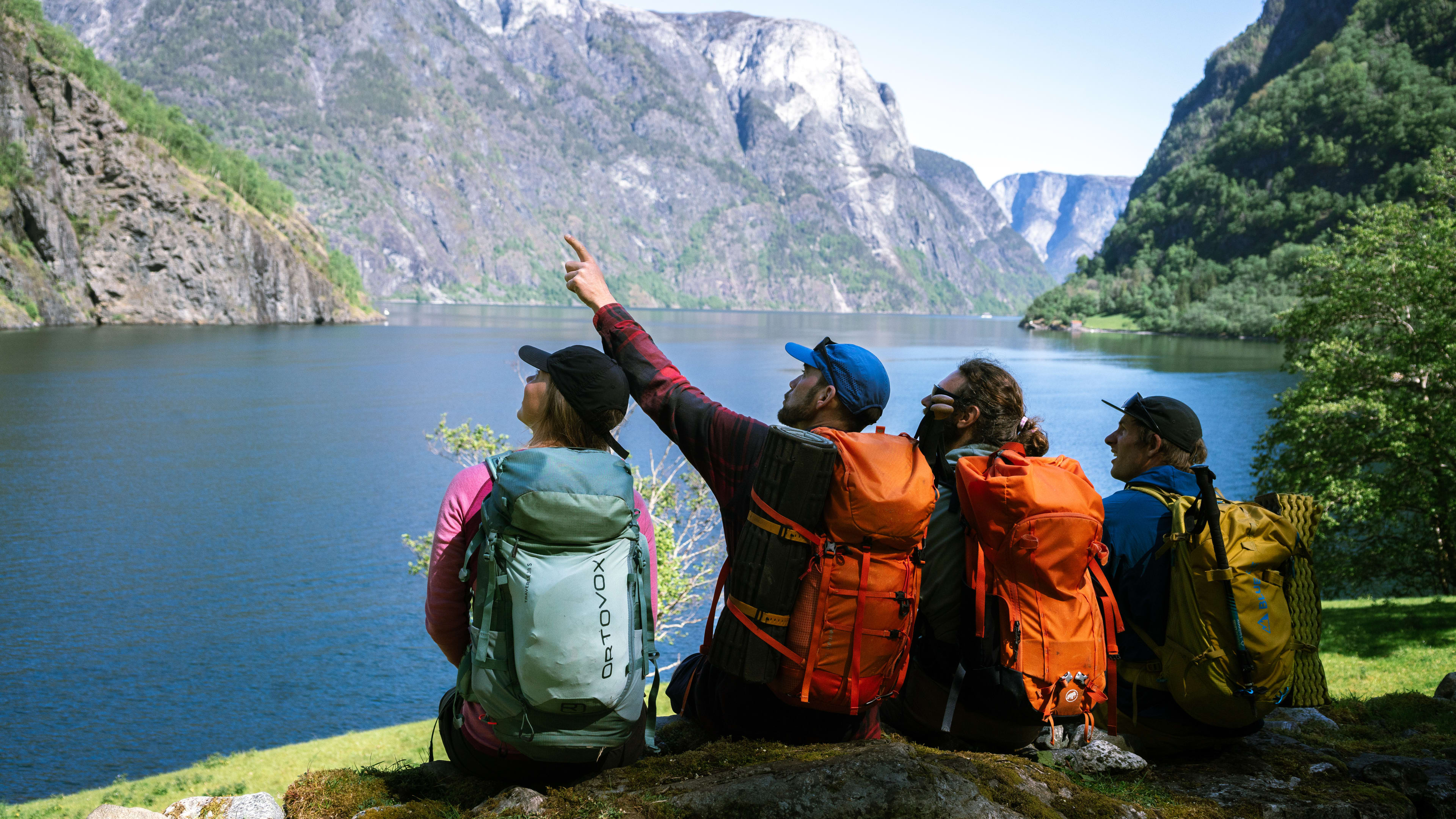 Fire turgåere tar pause under guidet tur på Kongeveien mens guide deler lokale historier med spektakulær norsk fjellnatur