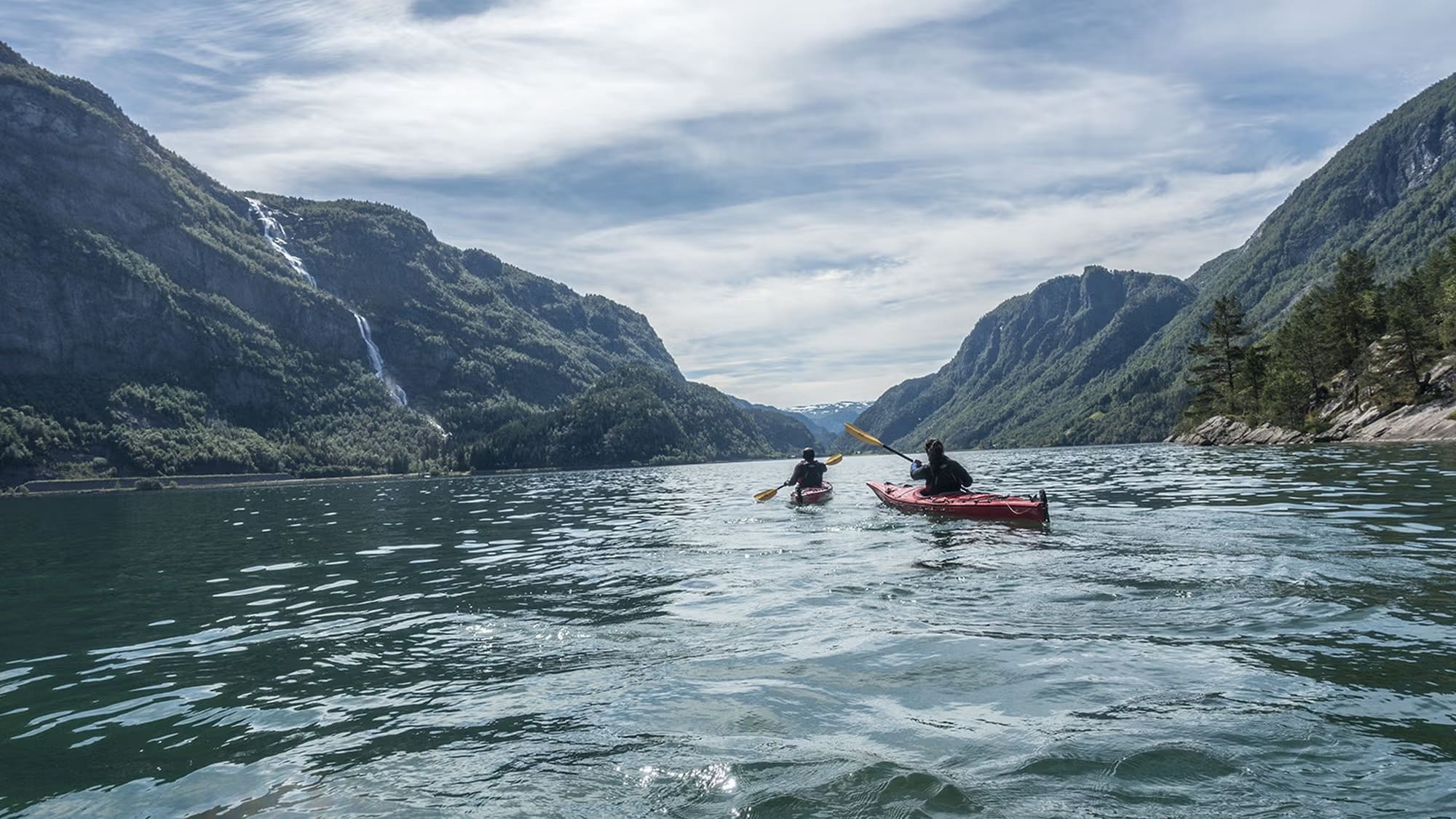 Kayak group paddling on Sandvinsvatnet Lake surrounded by mountains
