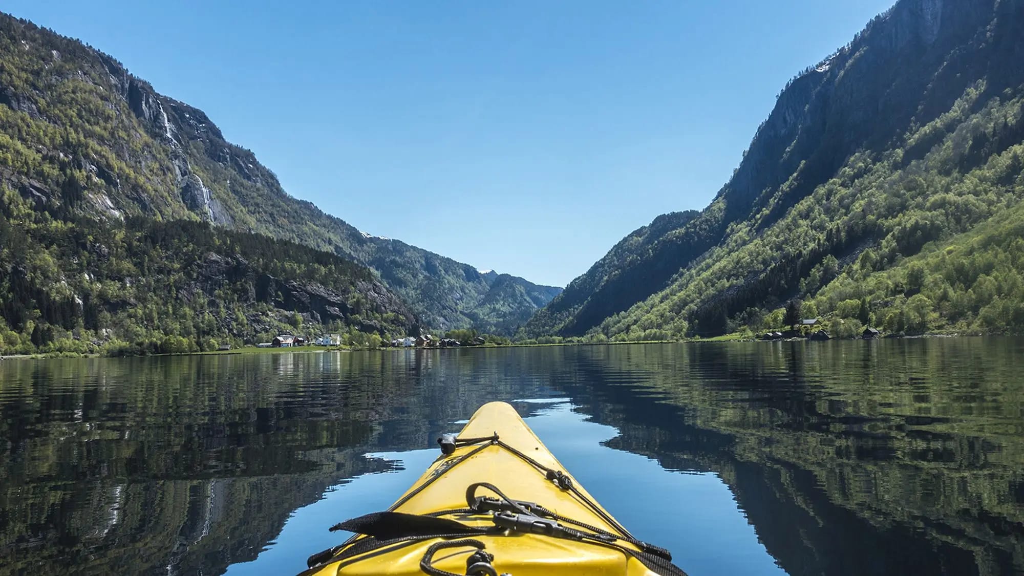 Yellow kayak on tranquil Sandvinsvatnet Lake with dramatic mountain valley backdrop