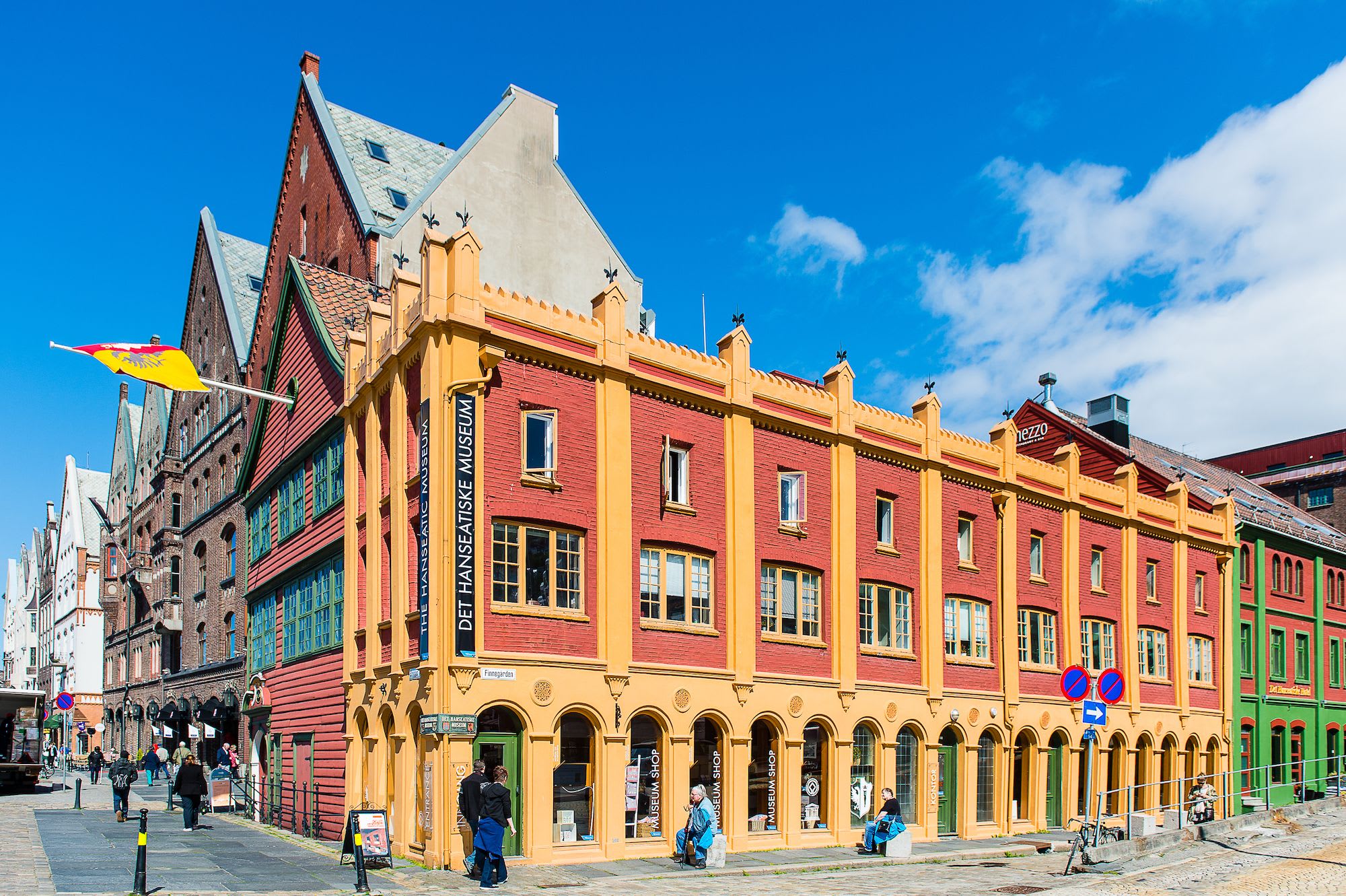 Colorful street scene with iconic red and yellow Hanseatic Museum, tourists and wooden buildings.