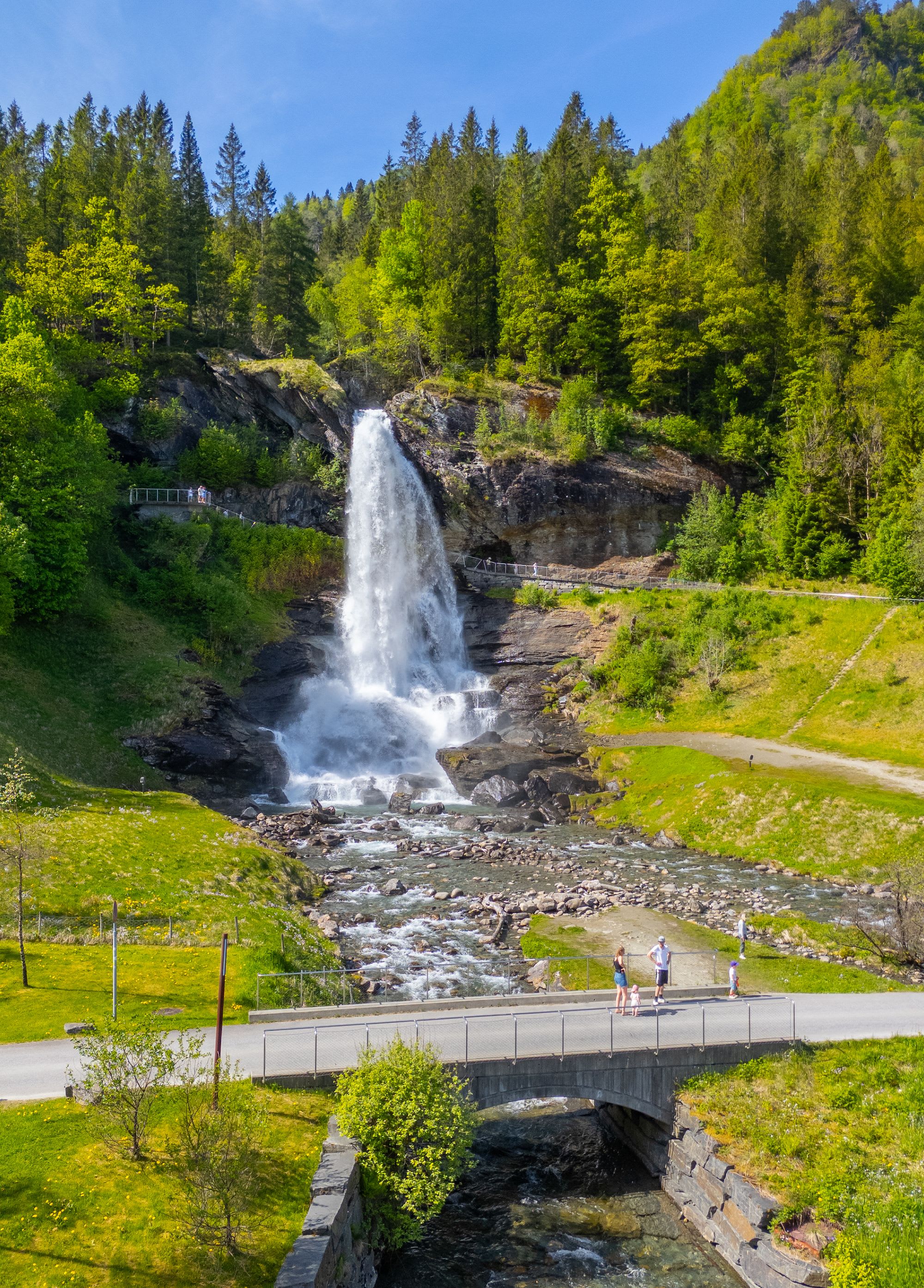 View of Steinsdalsfossen waterfall from the main road, showing the accessible path that leads visitors behind the 50-meter cascade