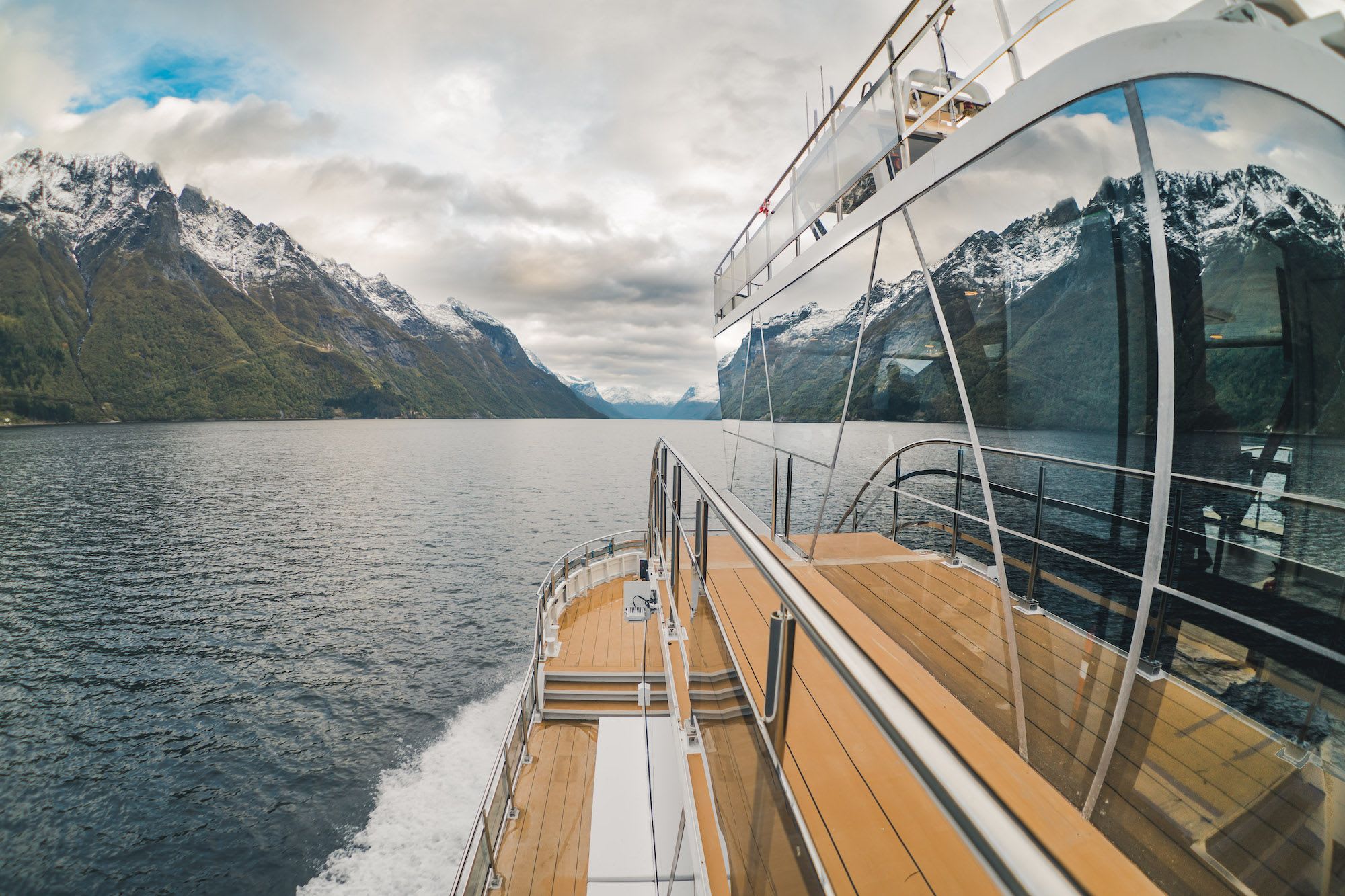 Moderne båt speiler fjordklipper i buede vinduer.