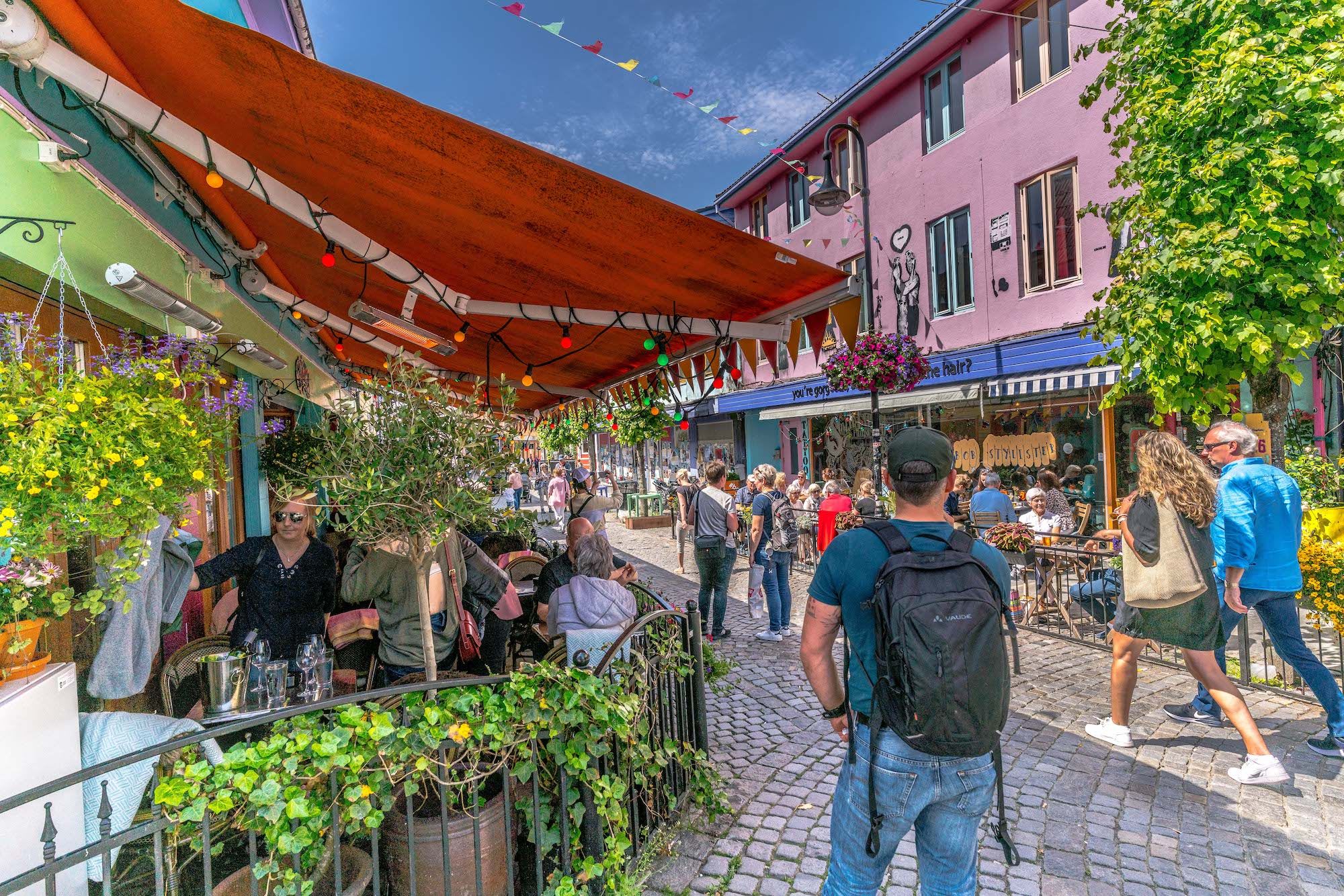 Travel Fargegata i Stavanger med kafeer, lys, blomster og folk.