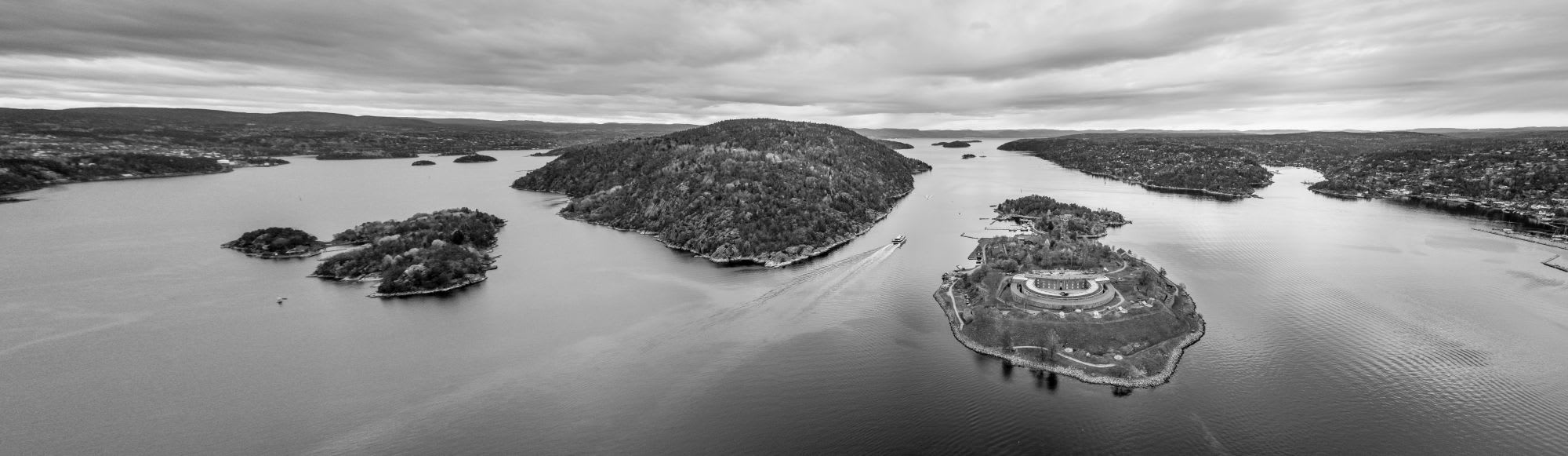 Aerial view of islands and ferry in peaceful waterway, with round structure on lush island.