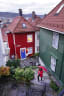 Woman with umbrella through narrow cobblestone street in Bergen on rainy day with colorful wooden houses