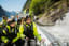 Group in yellow jackets smile and look at waterfall on fjord boat ride.