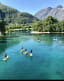 A group paddleboarding on a turquoise river with lush greenery and snow-capped peaks.