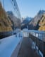 Boat side deck view of fjord cliffs mirrored in glossy windows.