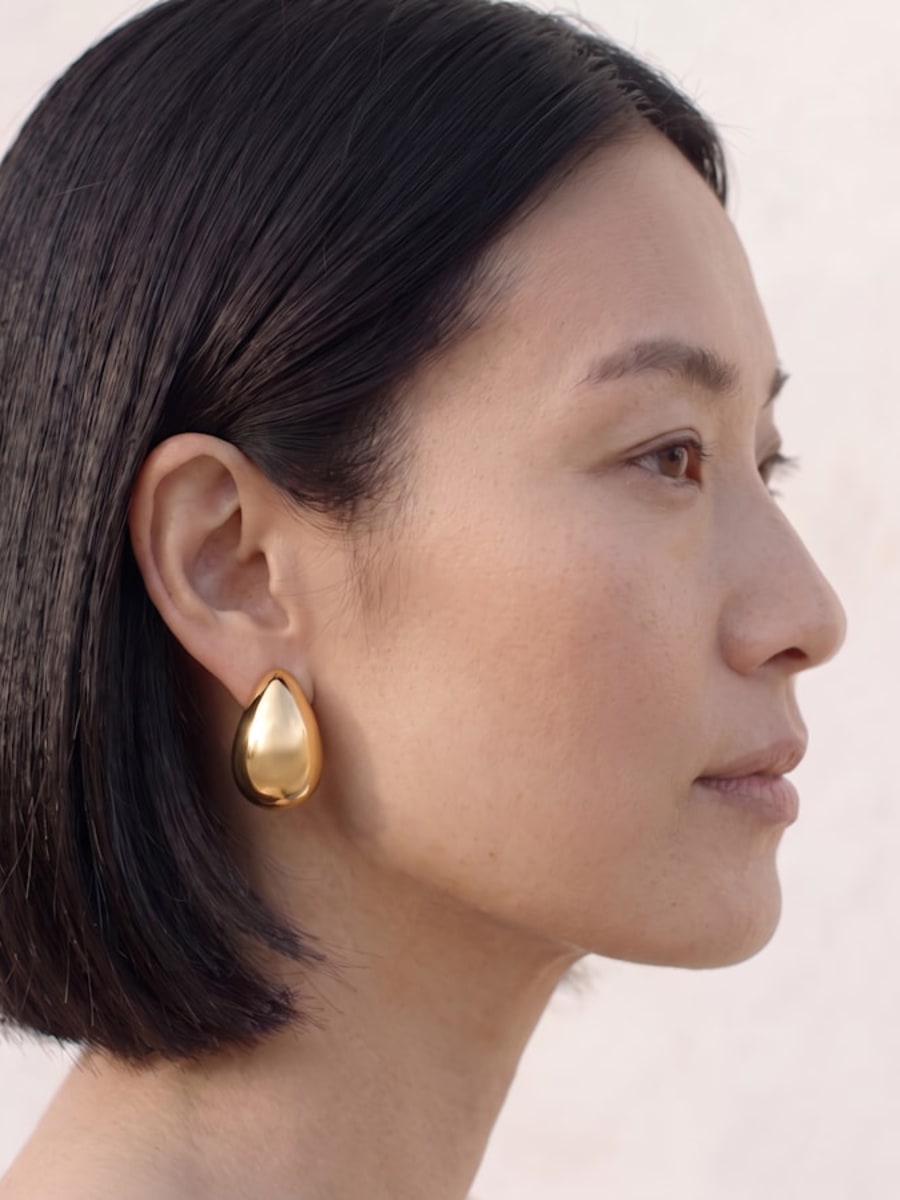 Profil portant une boucle d'oreille fleur dorée