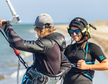 Kitesurf instructor explaining kite control to a student with radio helmet
